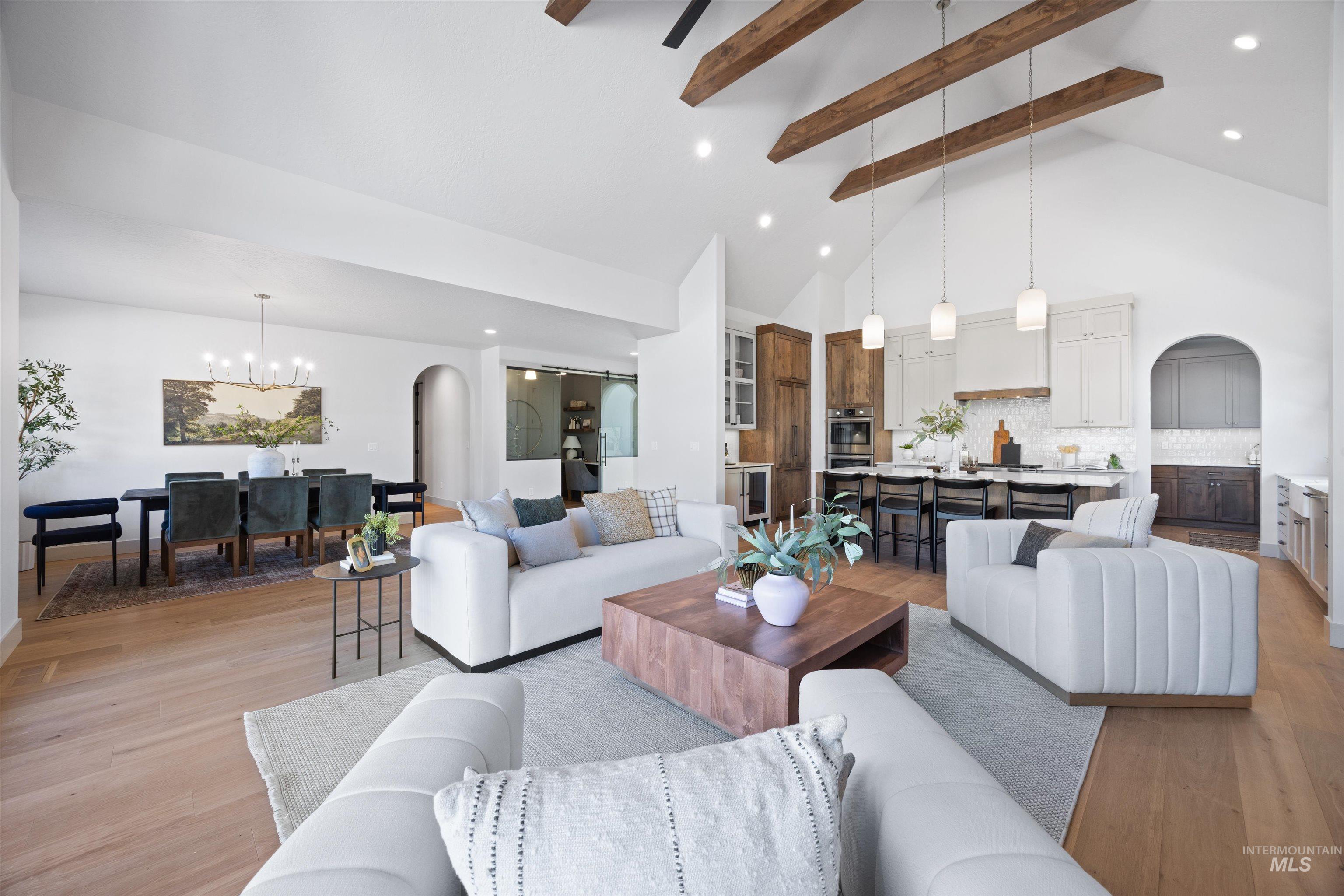 Living area with arched walkways, light wood-type flooring, hanging lights, and beverage cooler