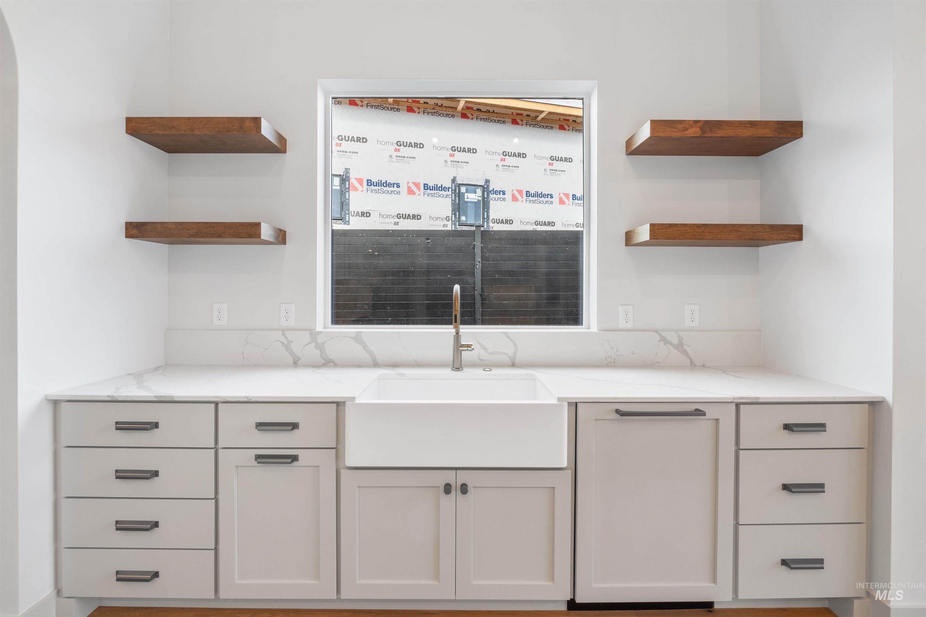 Bar area with open shelves, light stone counters, and white cabinets