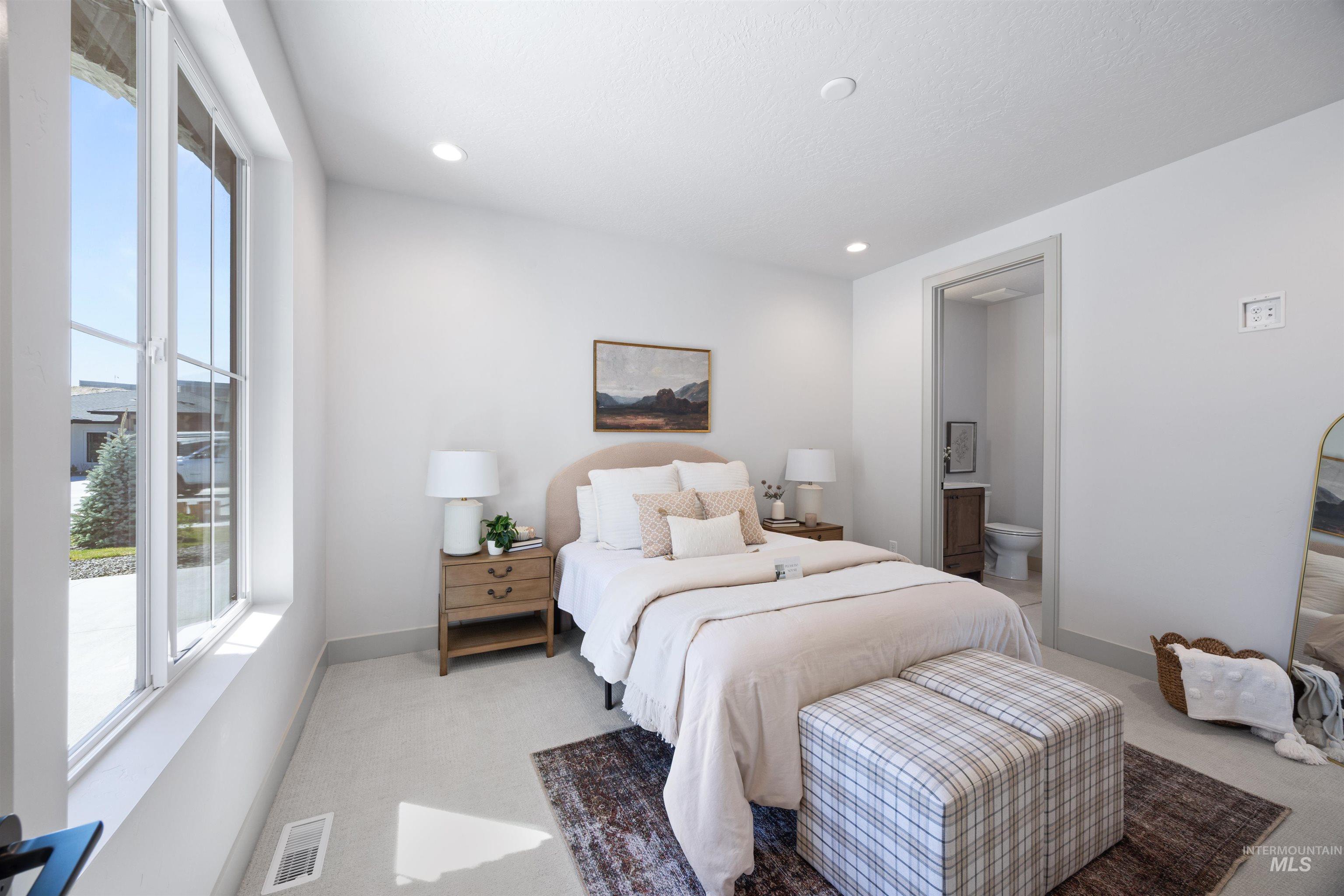 Bedroom with light colored carpet, ensuite bathroom, and recessed lighting