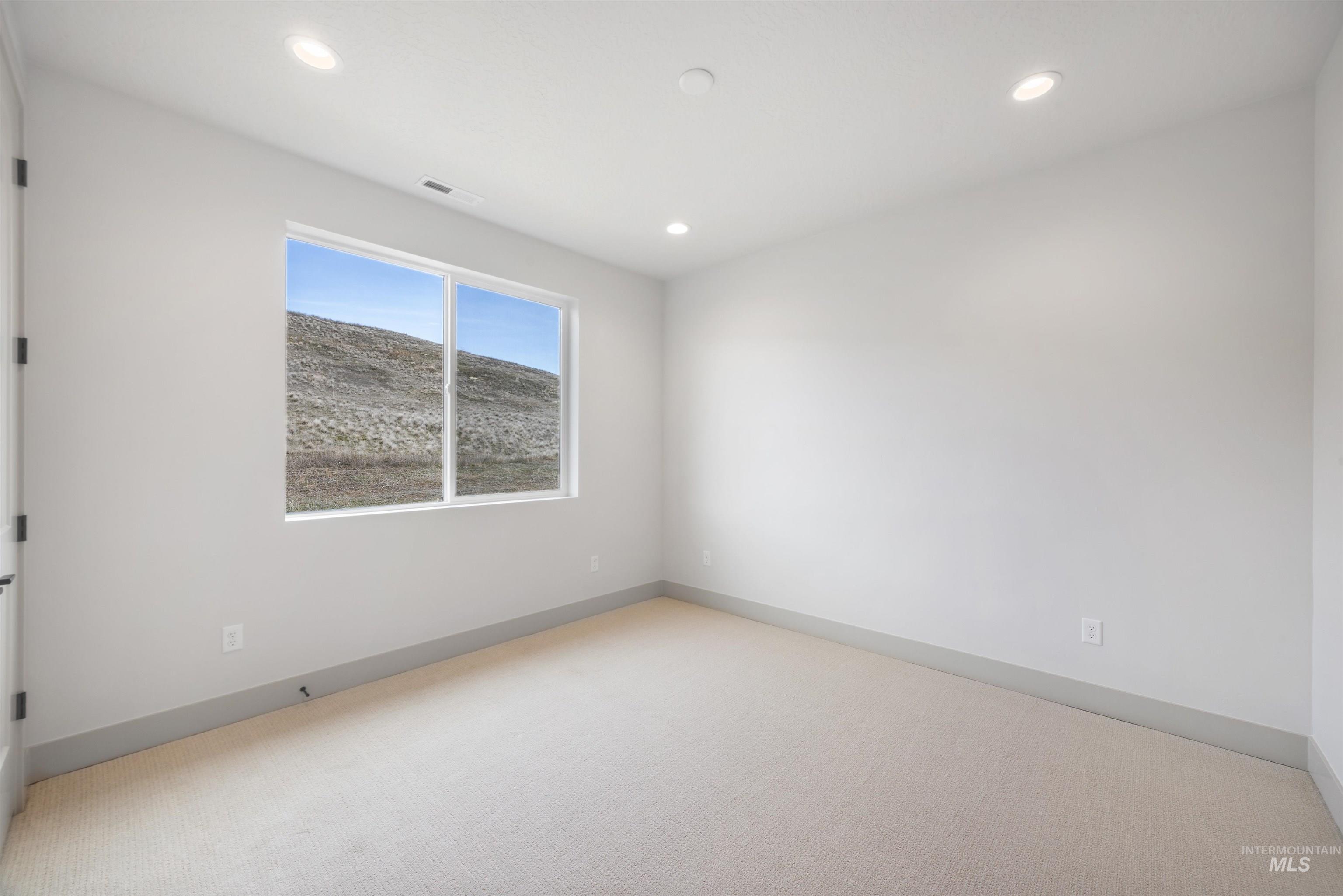 Unfurnished room with light colored carpet and recessed lighting