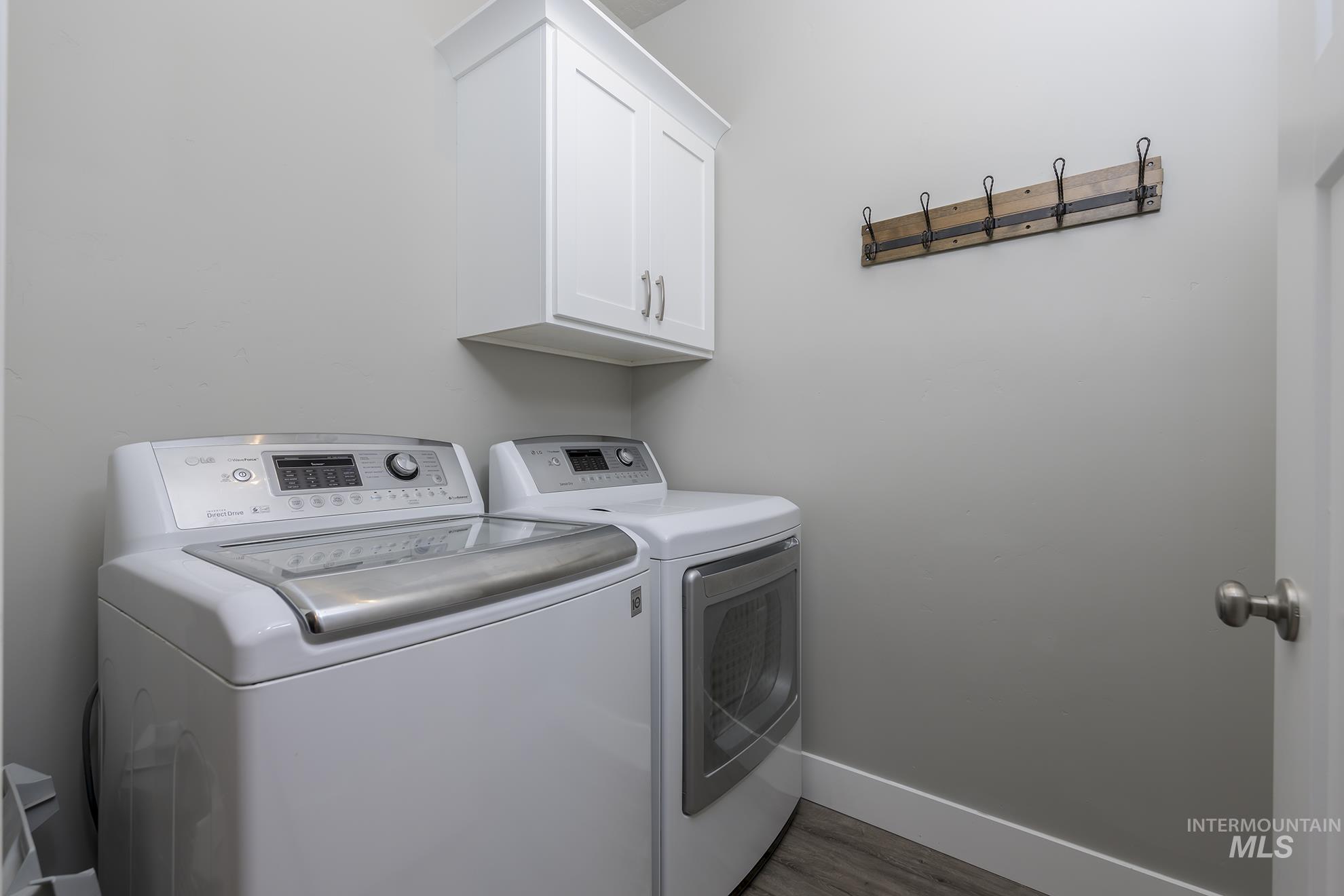 Laundry room featuring washer and clothes dryer, light wood-type flooring, and cabinet space