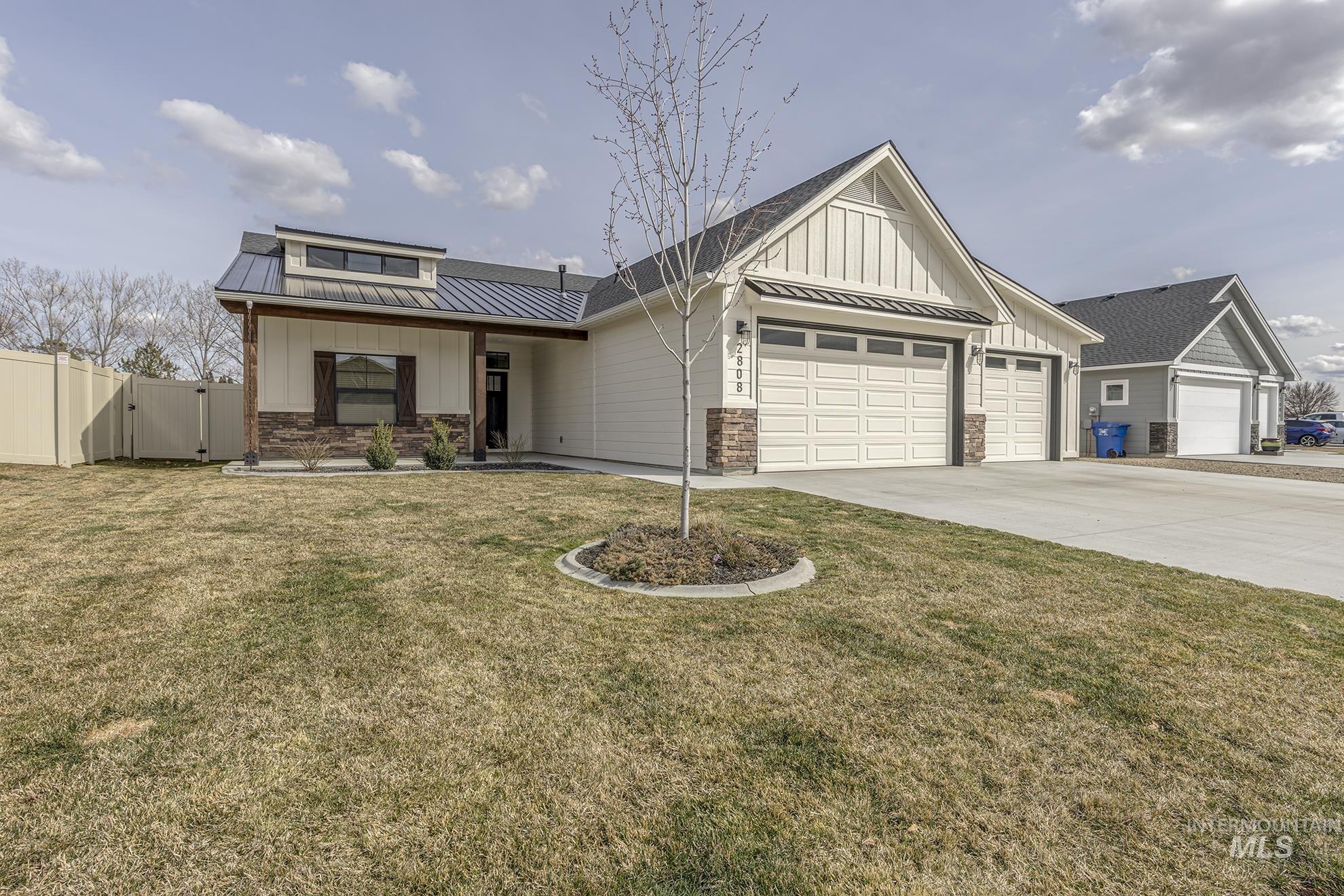 View of front of home featuring a gate, a garage, board and batten siding, and a standing seam roof