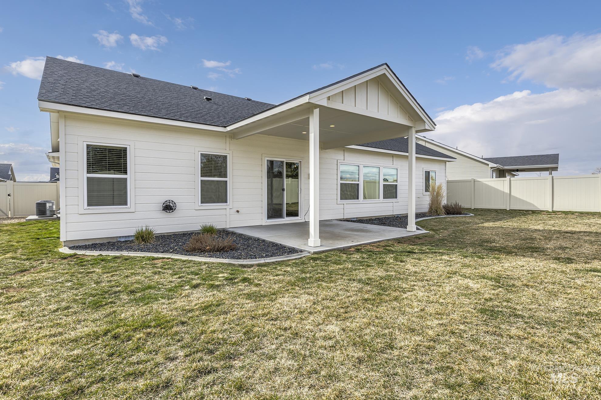 Back of house with a fenced backyard, a patio area, roof with shingles, and a gate