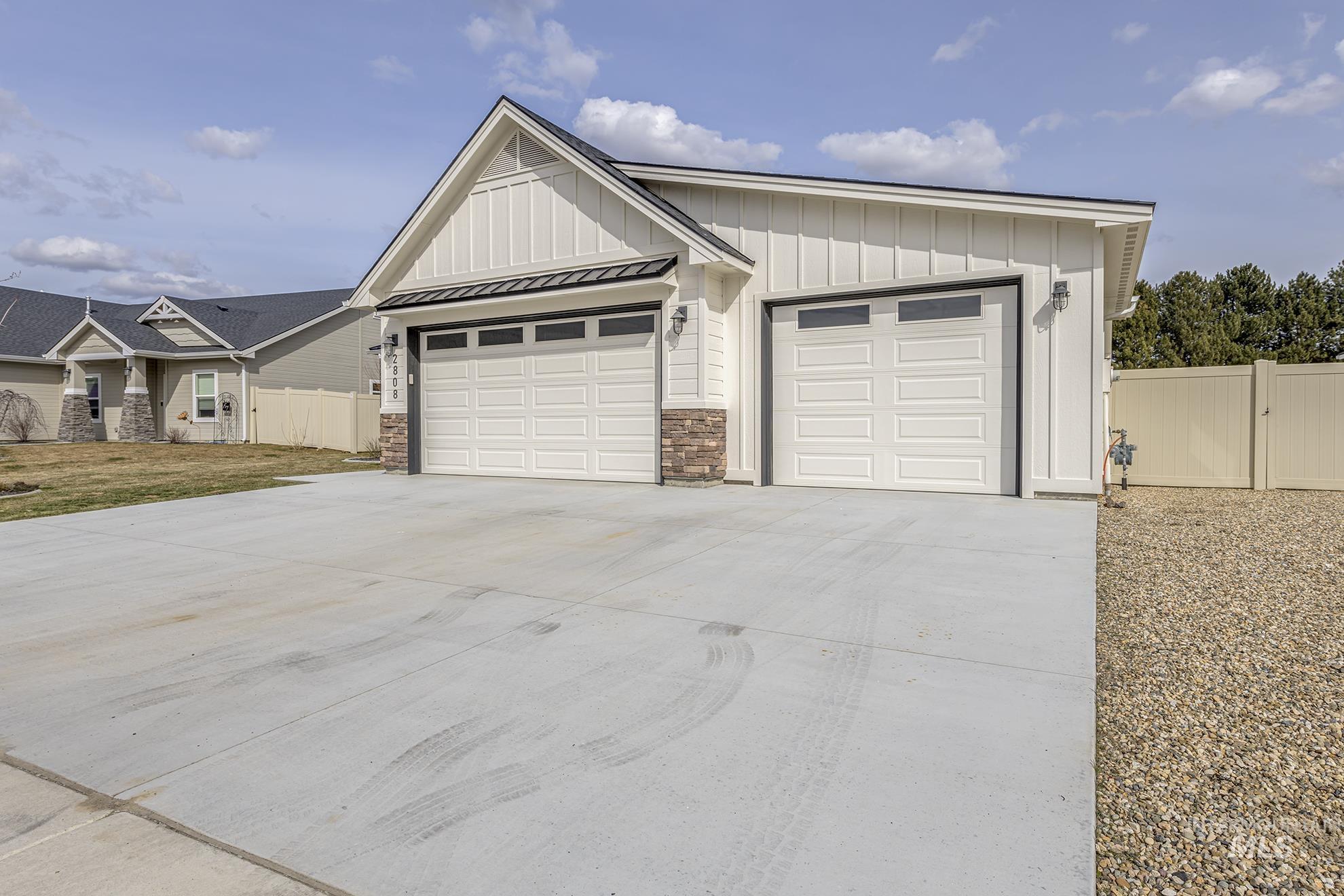 View of front of property featuring a gate, driveway, board and batten siding, a garage, and a standing seam roof