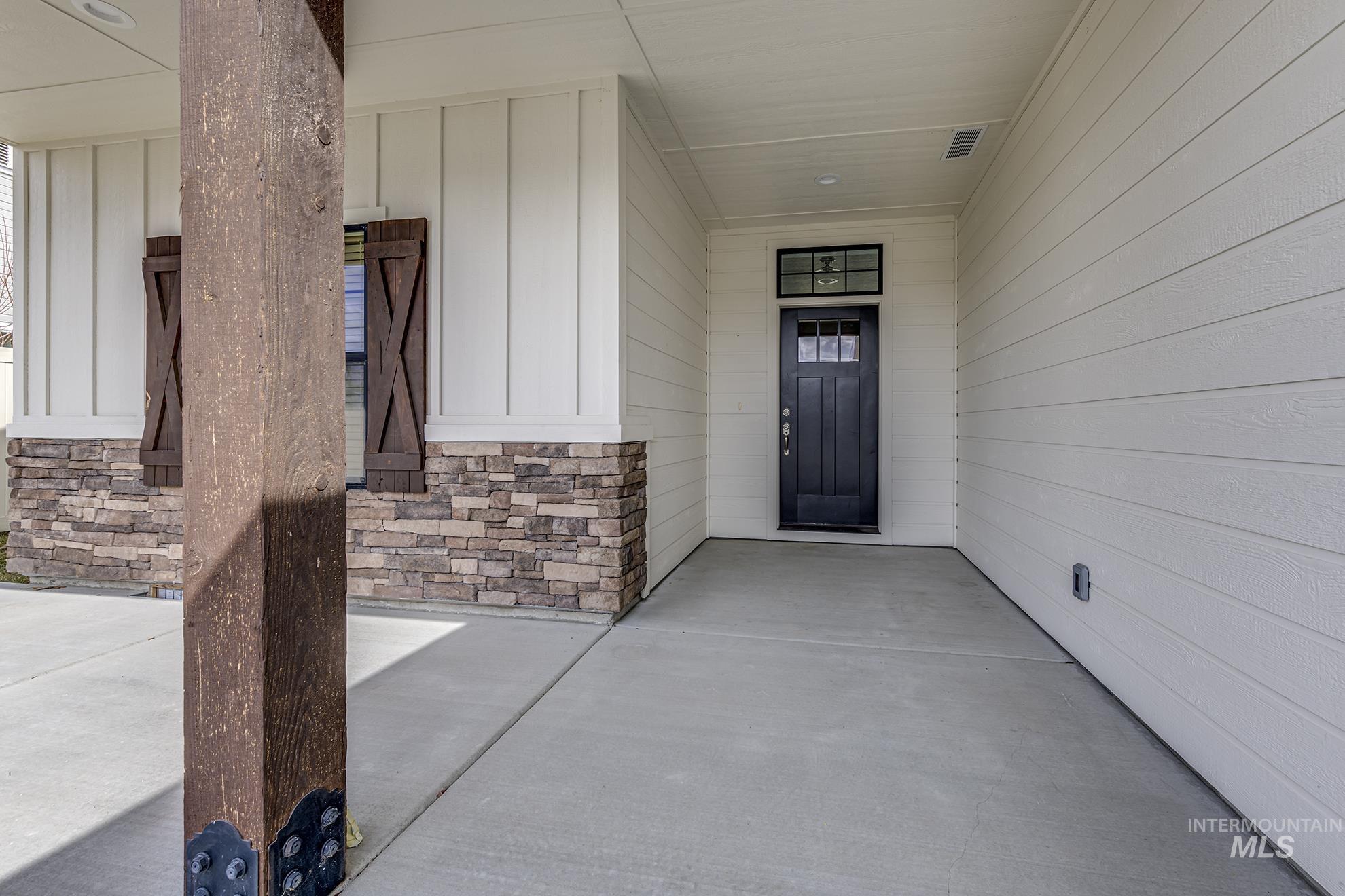 Property entrance with a porch, board and batten siding, and stone siding