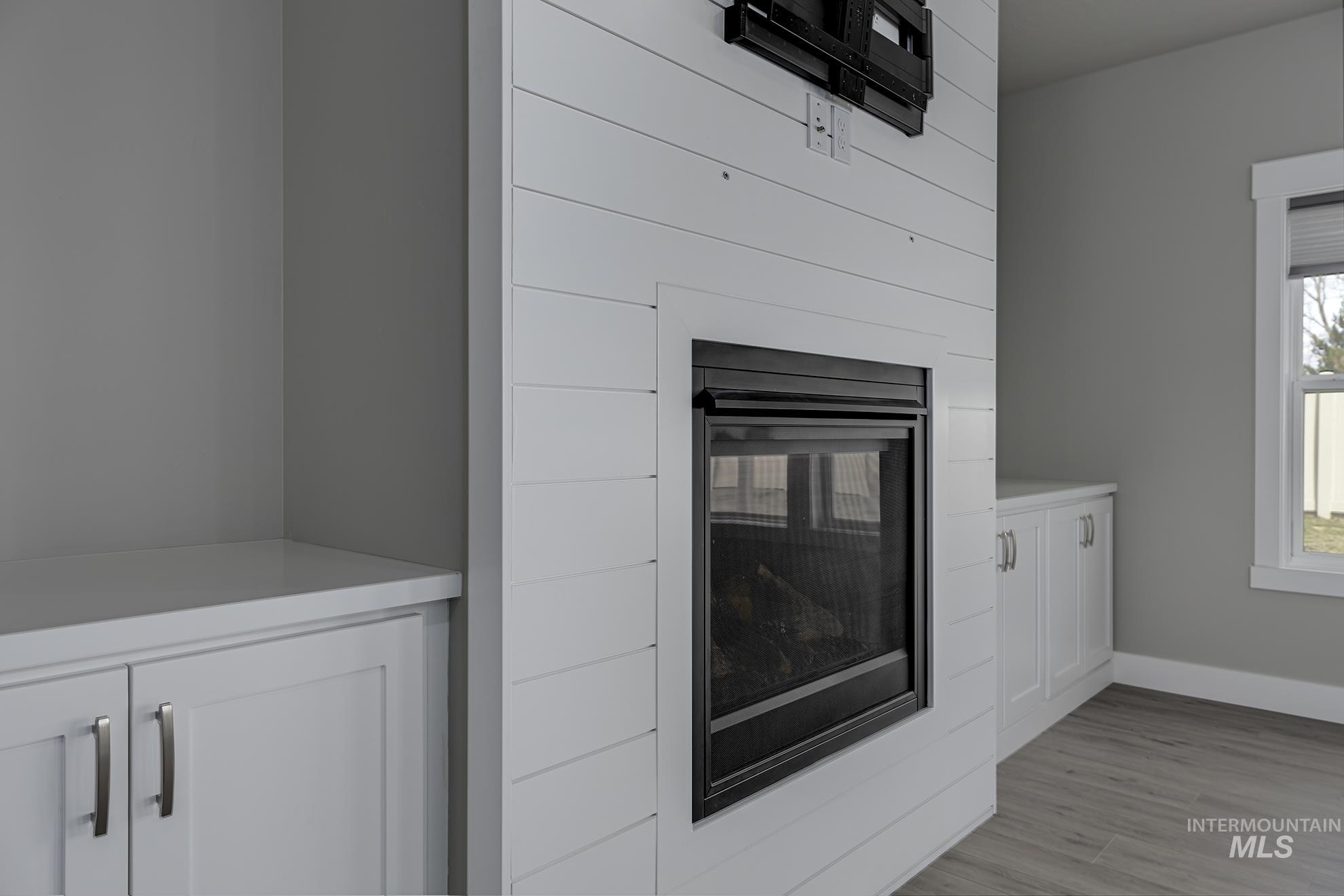 Detailed view of wood finished floors and a glass covered fireplace