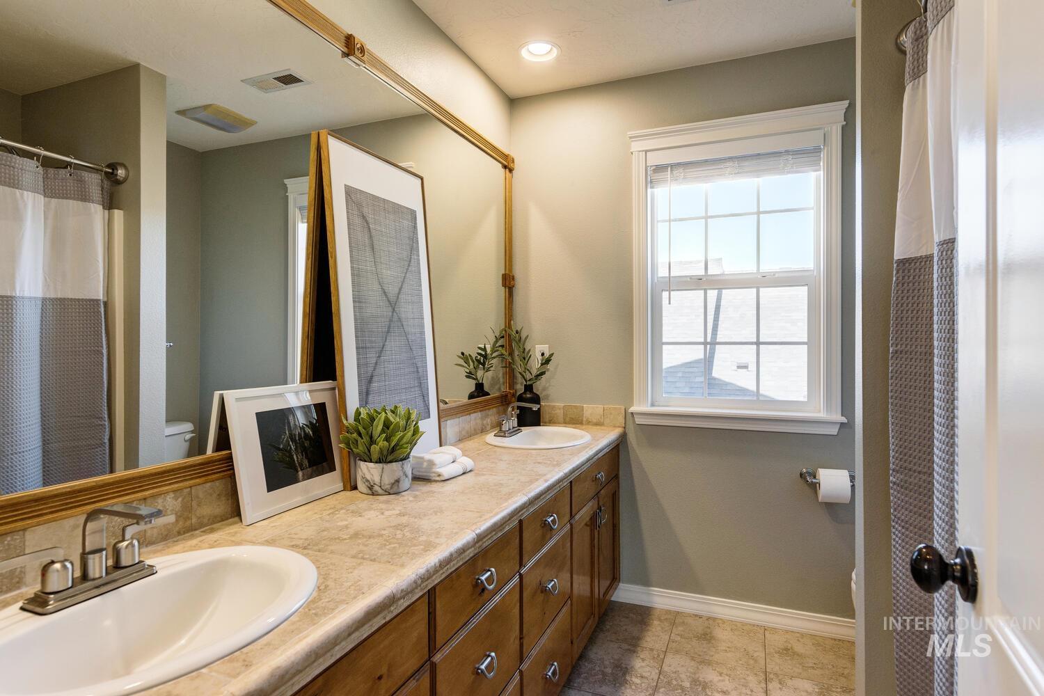 Full bathroom with double vanity and light tile patterned flooring