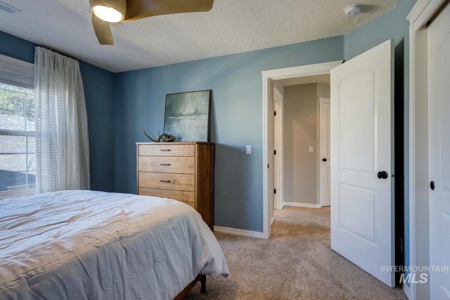 Bedroom with carpet floors, a textured ceiling, and ceiling fan
