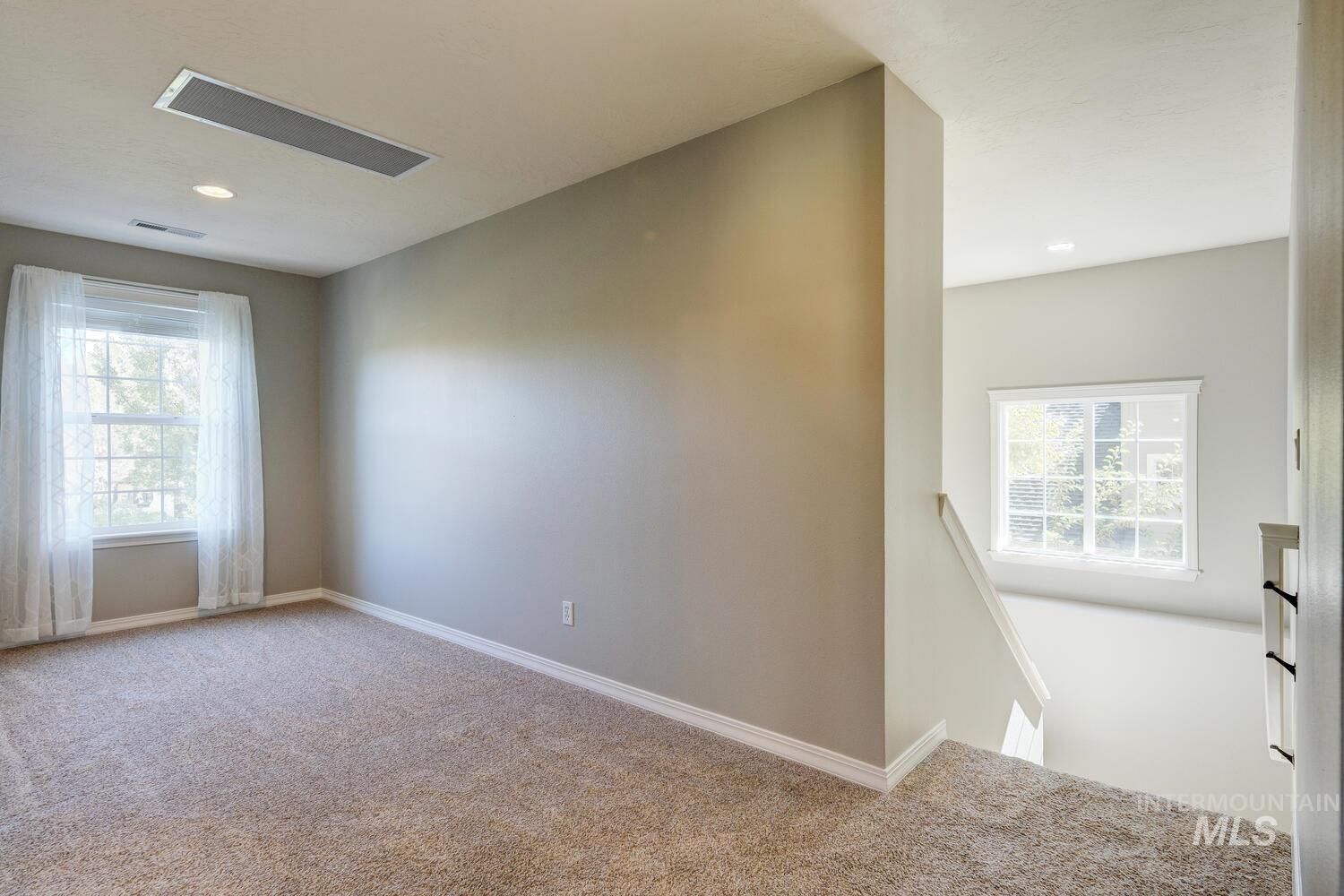 Unfurnished room featuring light colored carpet and healthy amount of natural light