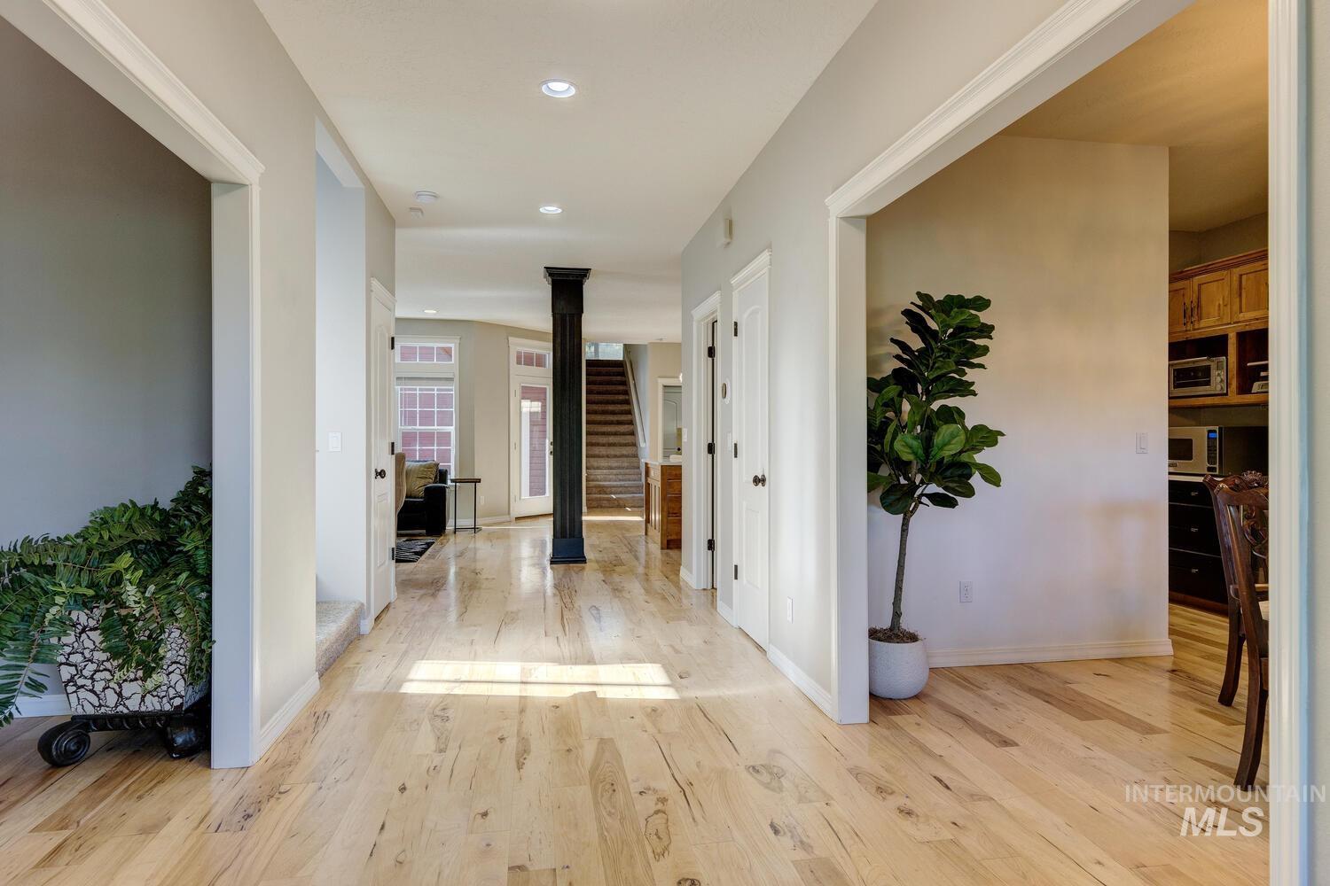 Hall with light wood-type flooring, ornate columns, and recessed lighting