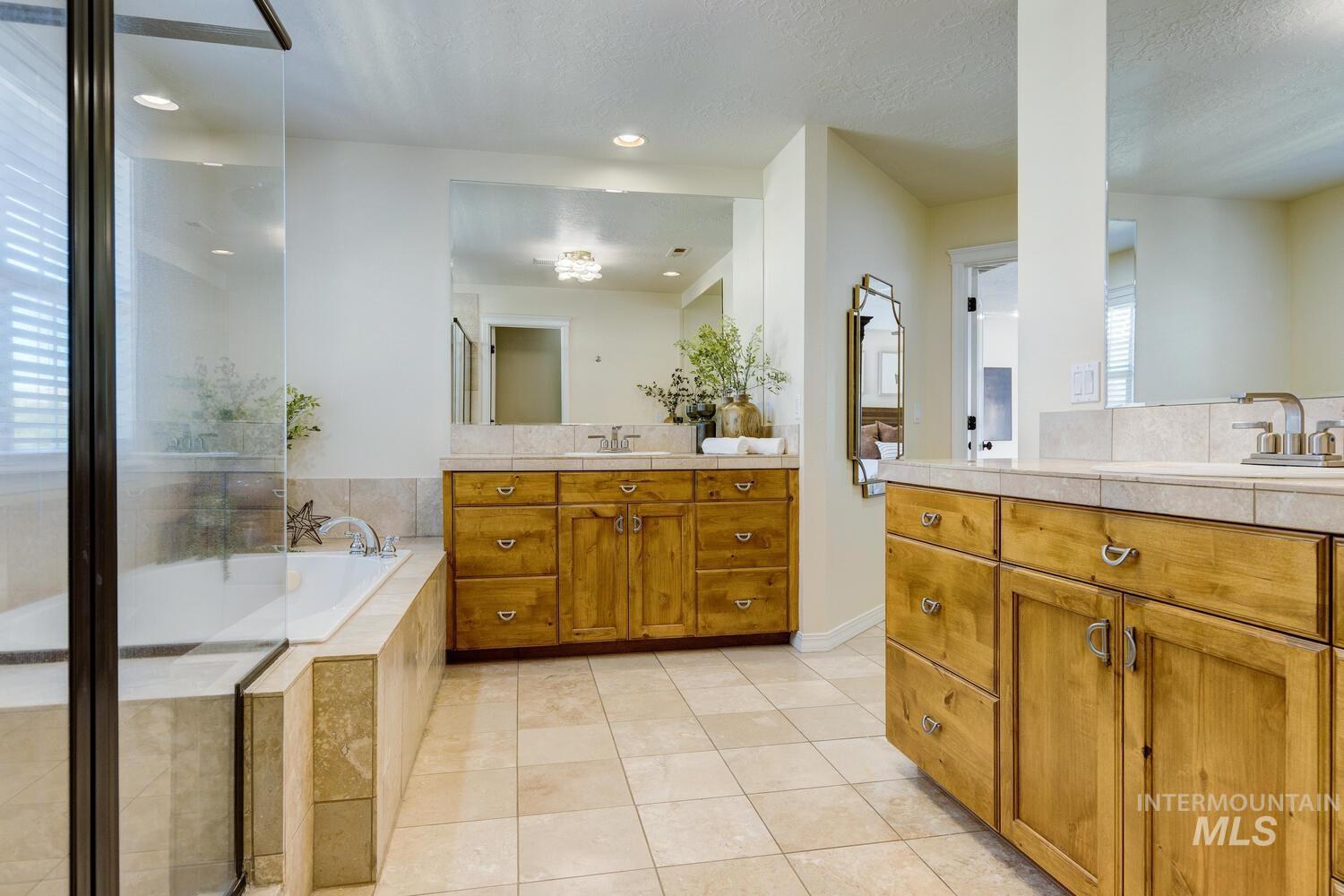 Full bathroom with two vanities, light tile patterned floors, a bath, recessed lighting, and a textured ceiling