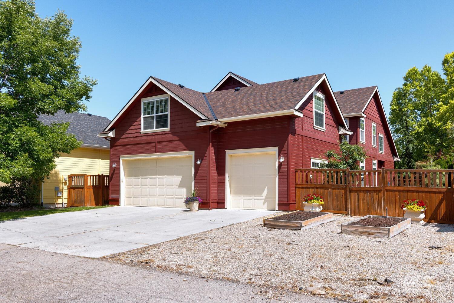 View of front of property featuring driveway, a garden, a garage, and roof with shingles
