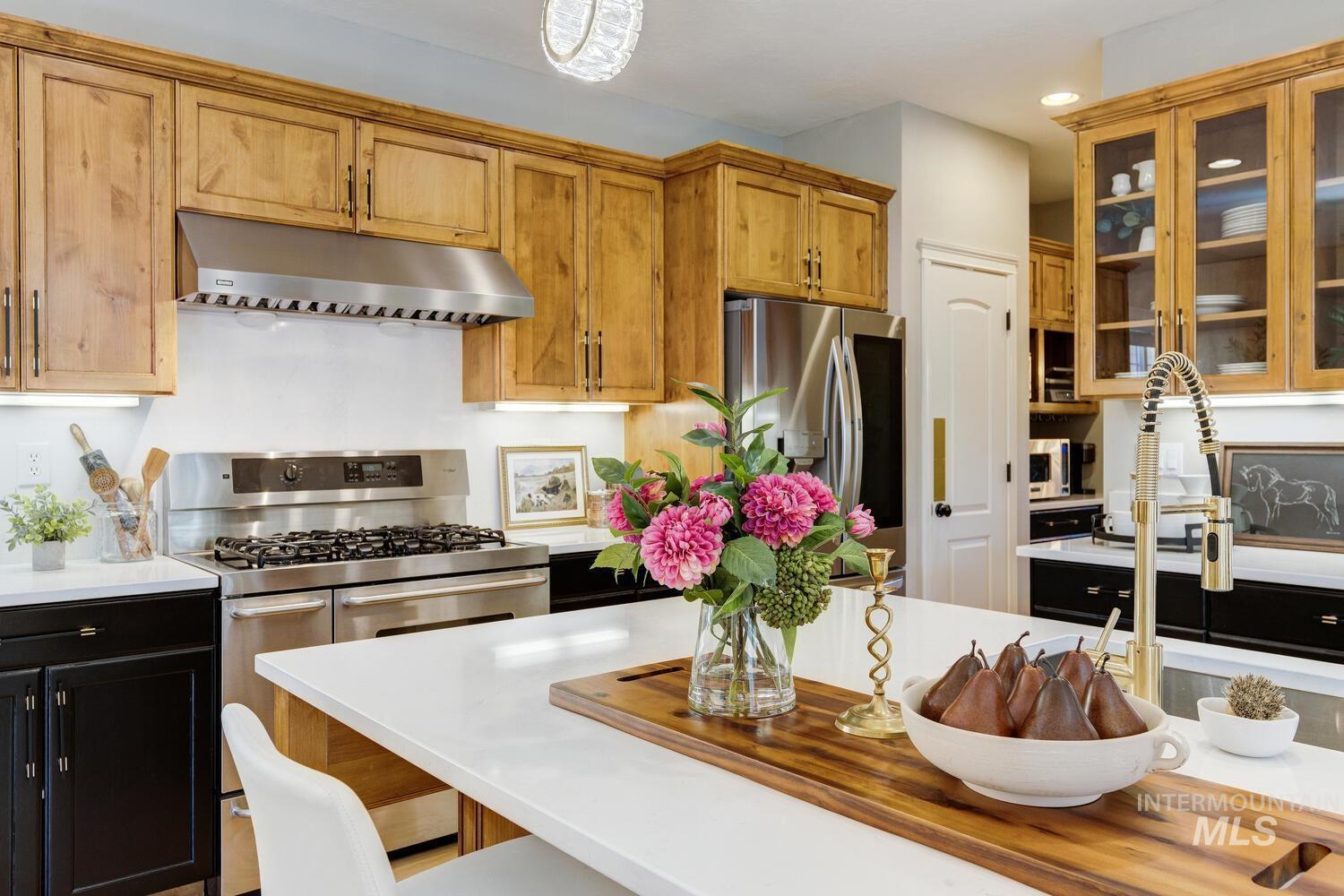 Kitchen featuring stainless steel appliances, under cabinet range hood, glass insert cabinets, recessed lighting, and a breakfast bar area