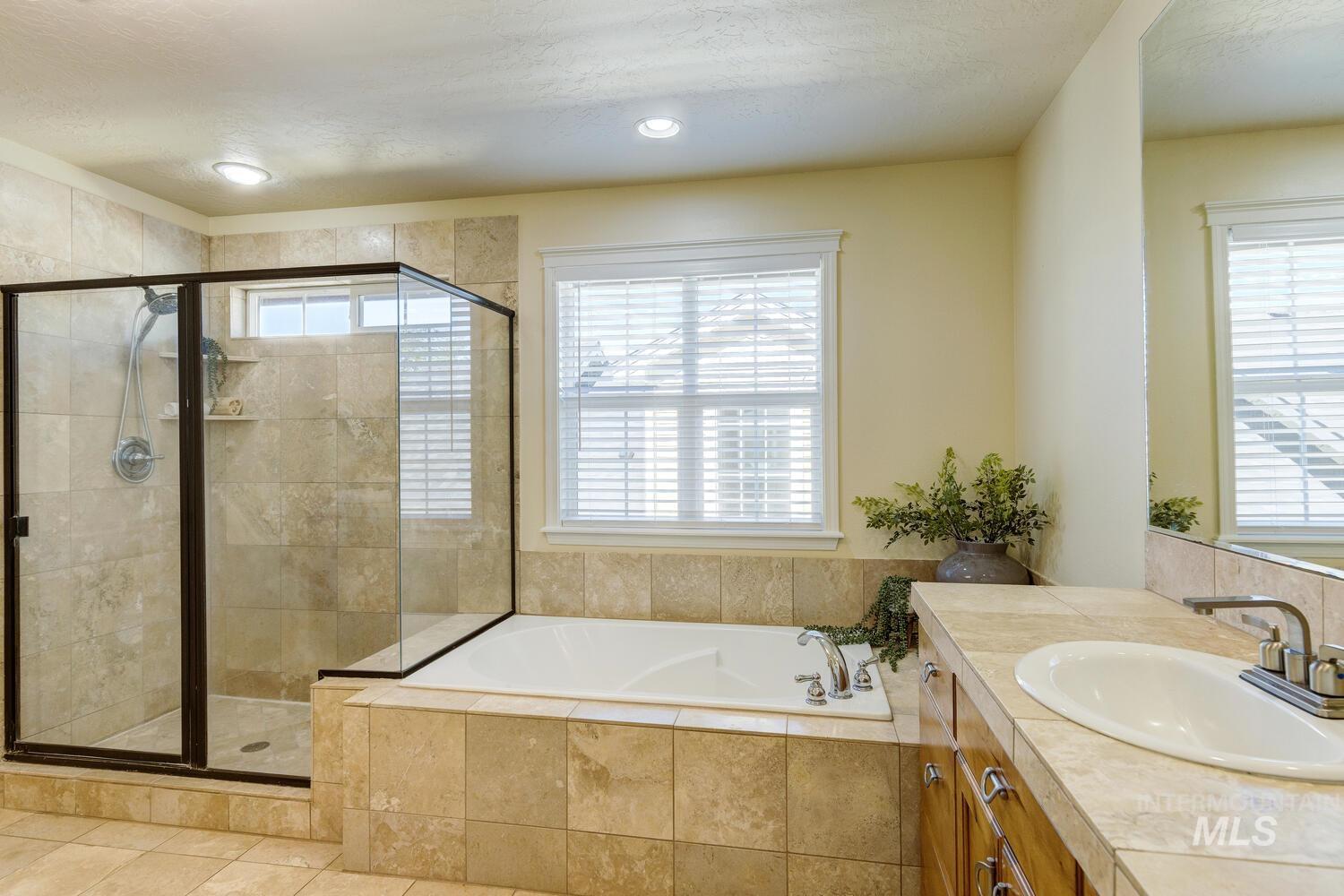 Full bathroom featuring vanity, a shower stall, a garden tub, a textured ceiling, and recessed lighting