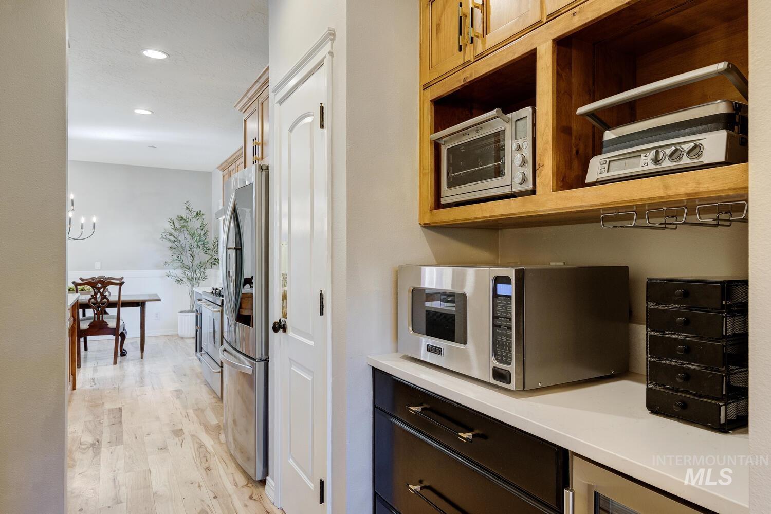 Kitchen with stainless steel appliances, light wood-type flooring, recessed lighting, a chandelier, and light stone counters