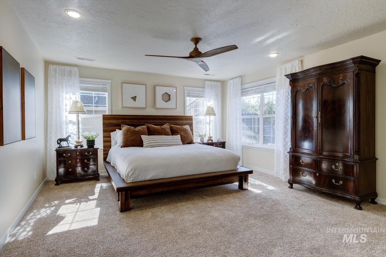 Bedroom with light carpet, a textured ceiling, and a ceiling fan