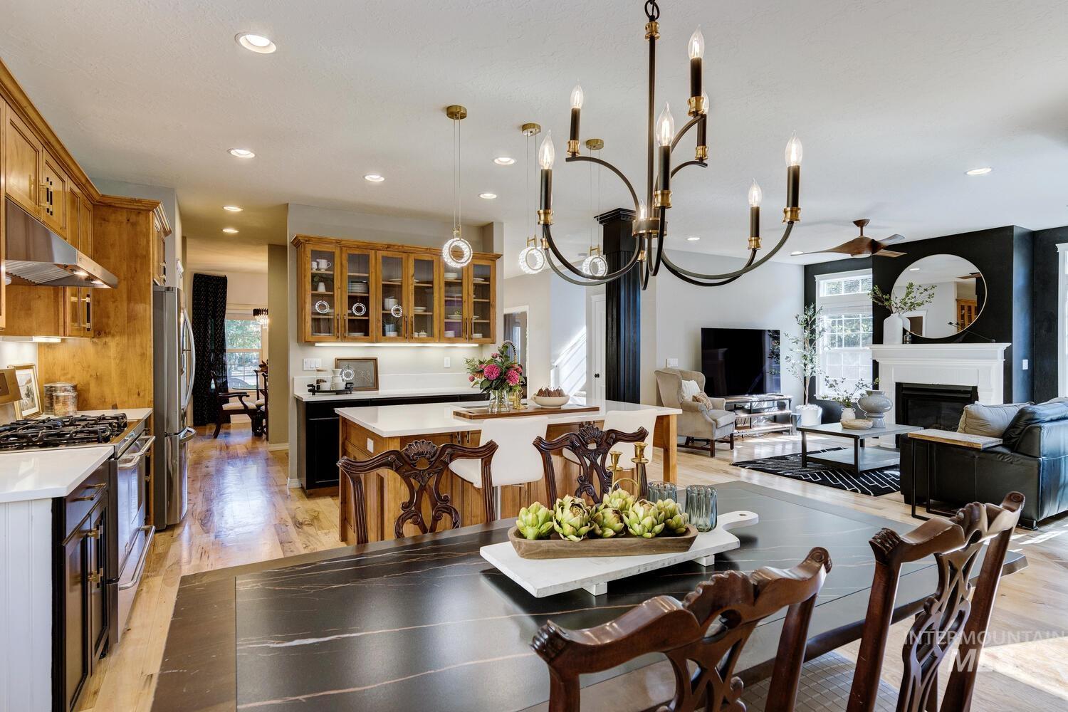 Dining room featuring healthy amount of natural light, a glass covered fireplace, light wood finished floors, recessed lighting, and a chandelier