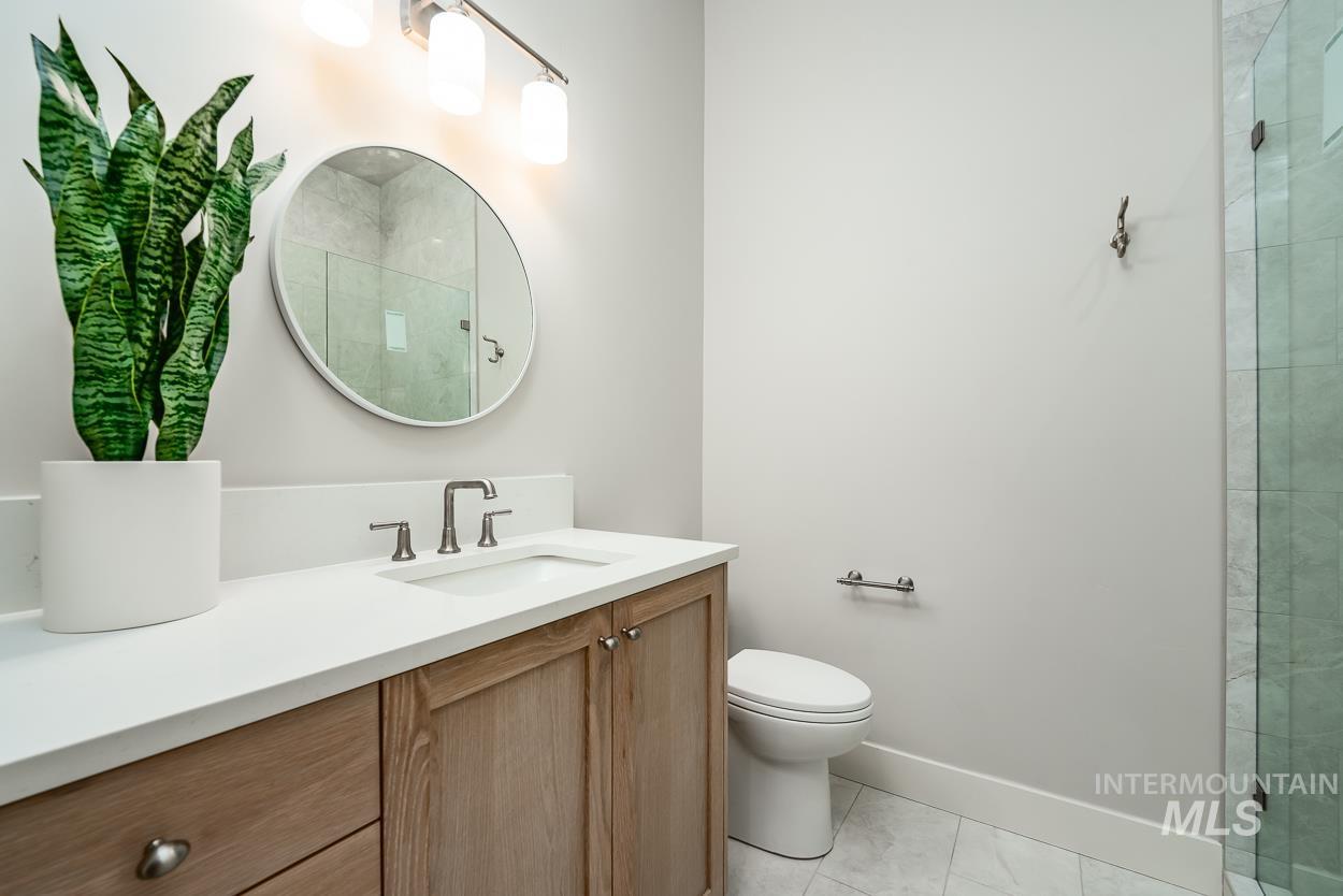 Full bath with vanity, tiled shower, and light tile patterned flooring