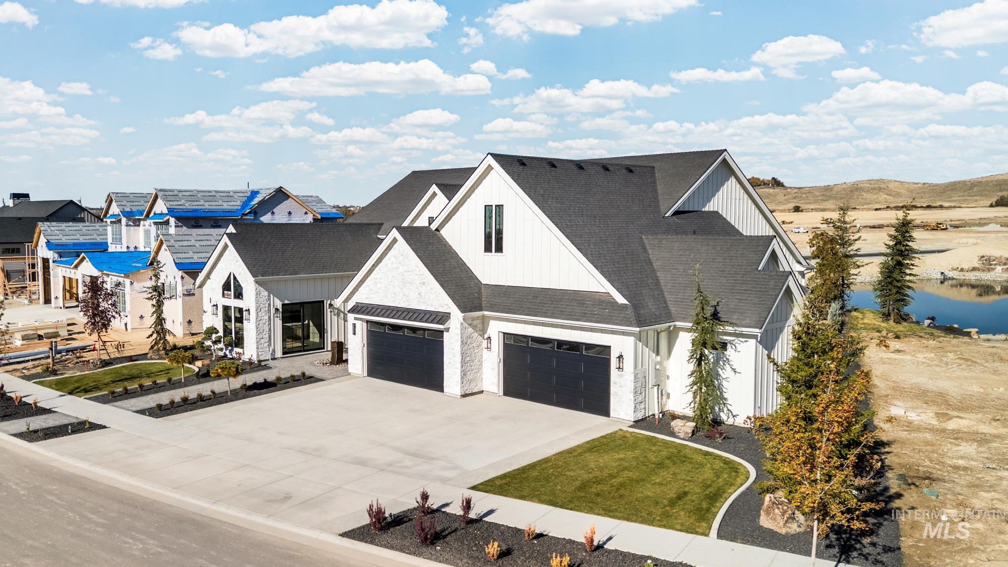 View of front of house with board and batten siding, driveway, and roof with shingles