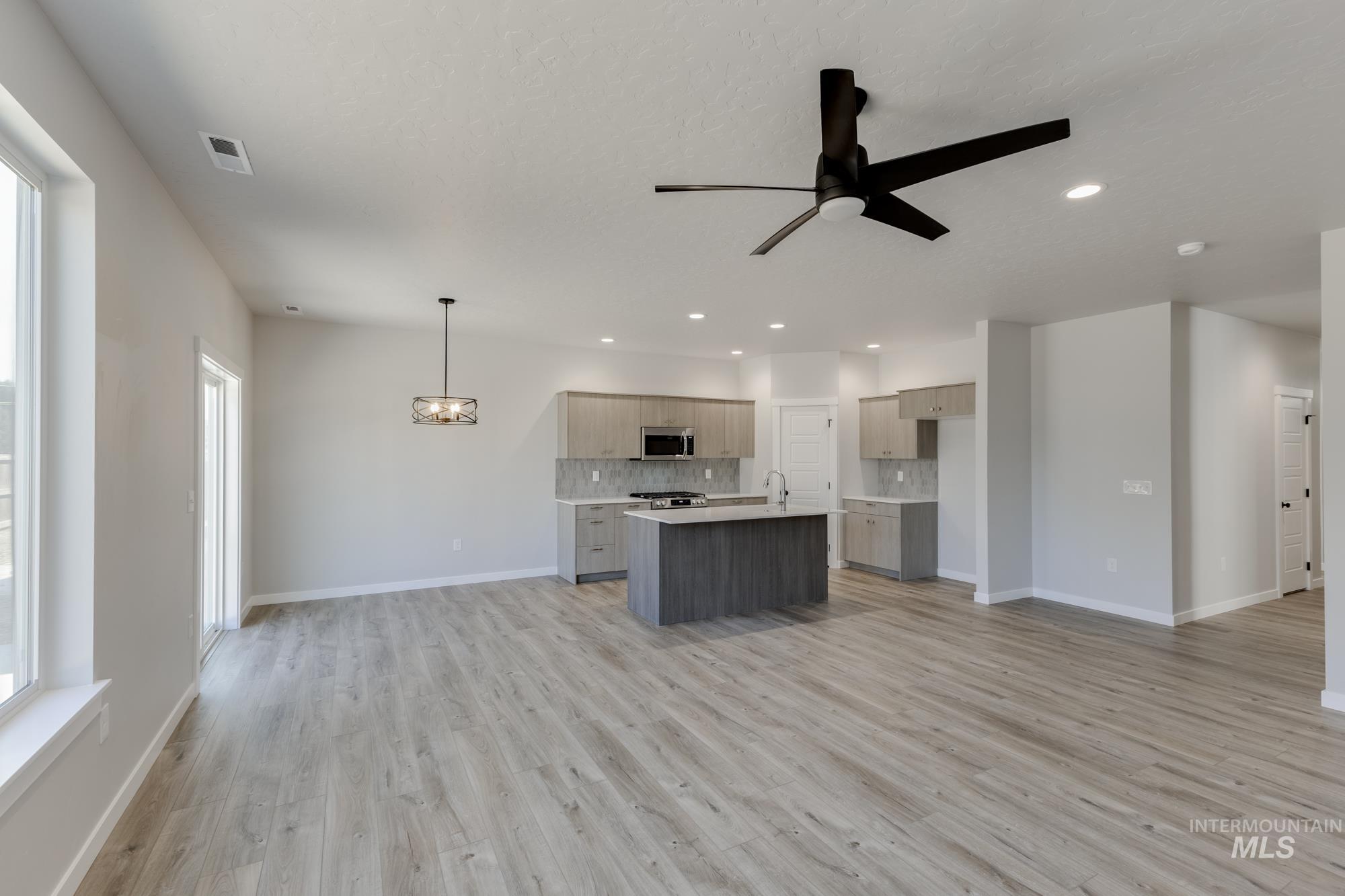 Kitchen with open floor plan, decorative backsplash, a kitchen island with sink, light wood-type flooring, and recessed lighting