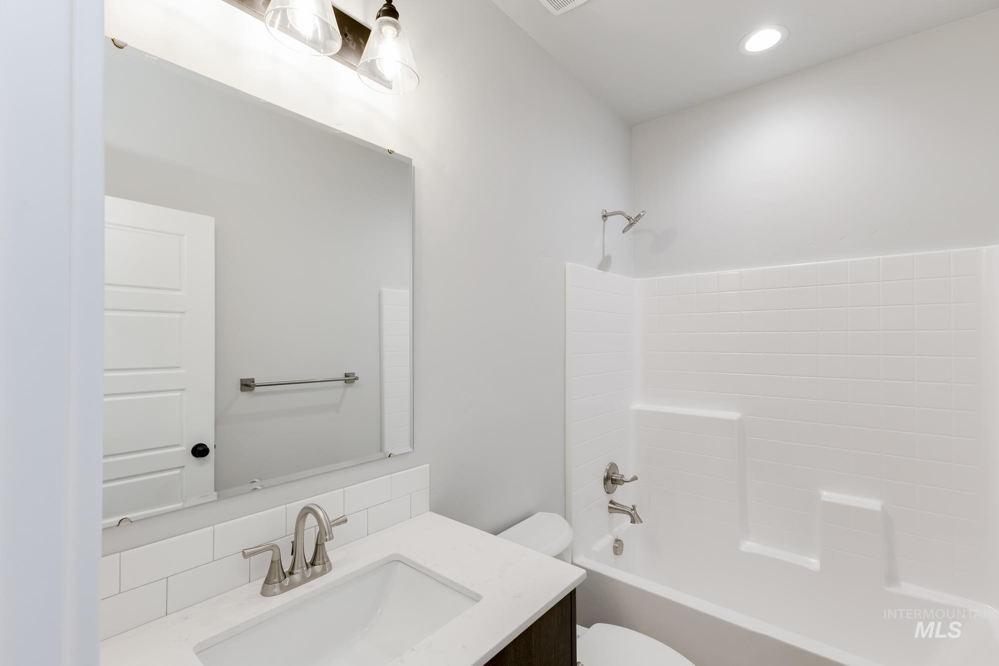 Bathroom with vanity, bathtub / shower combination, and recessed lighting