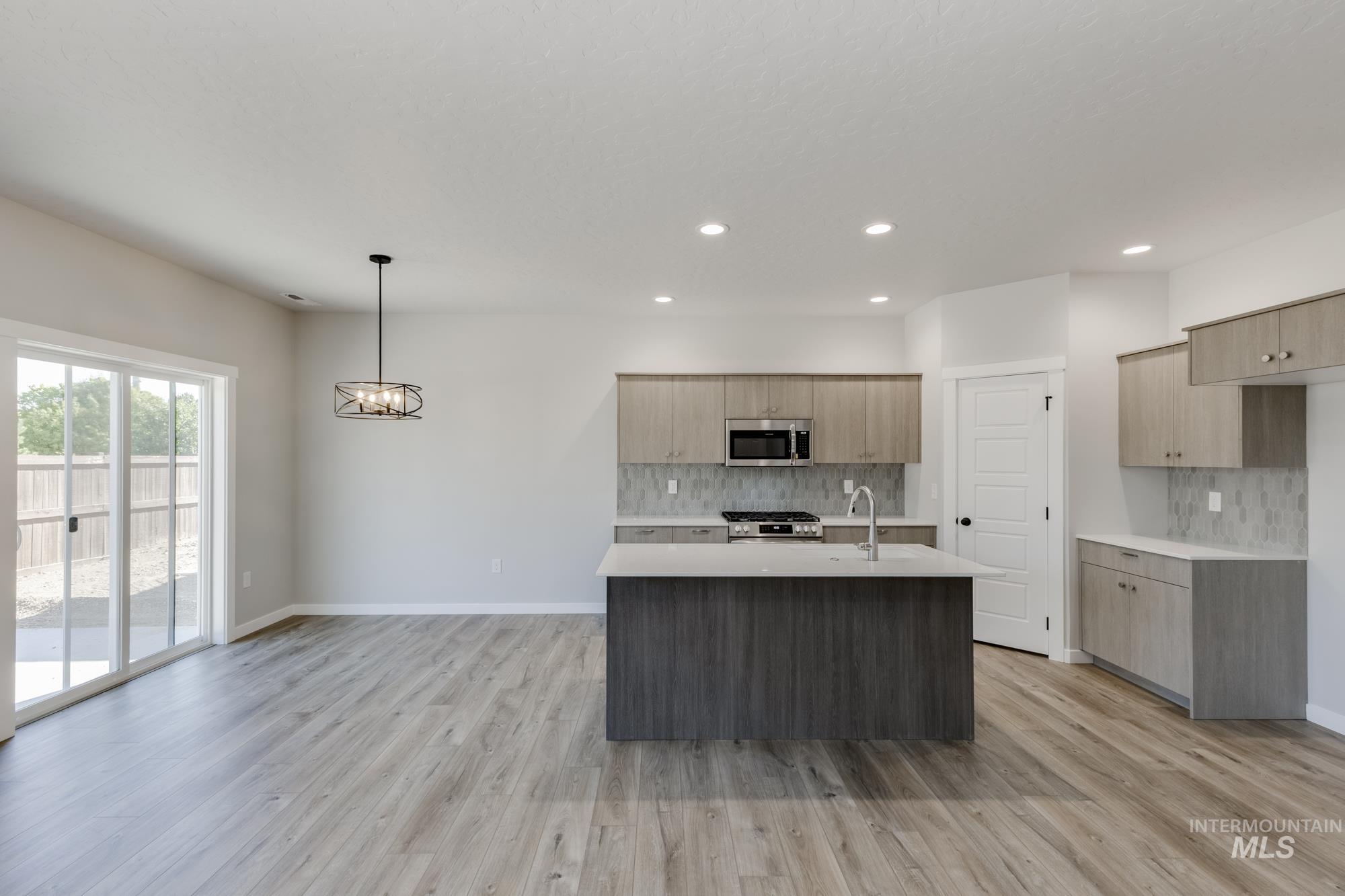 Kitchen with a center island with sink, hanging light fixtures, light wood-type flooring, modern cabinets, and recessed lighting