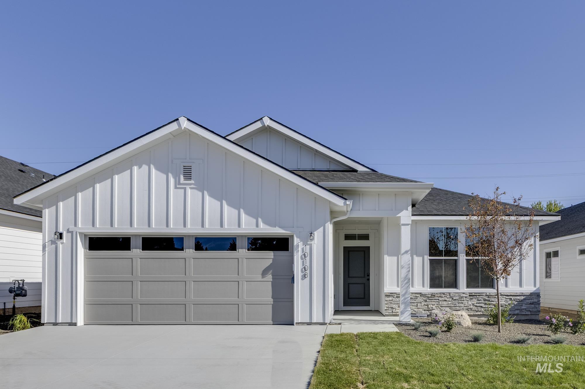 Modern inspired farmhouse with board and batten siding, roof with shingles, an attached garage, driveway, and a front lawn