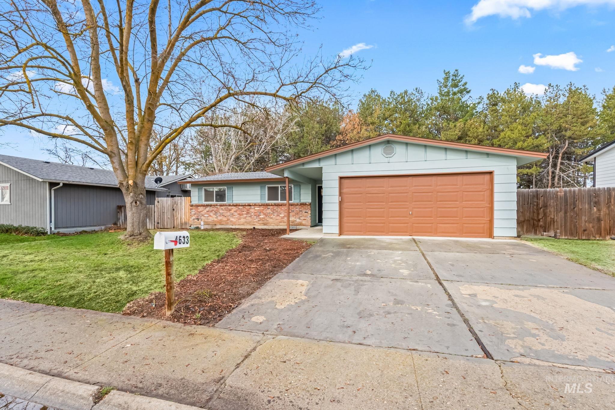 Ranch-style home featuring driveway, an attached garage, board and batten siding, and brick siding