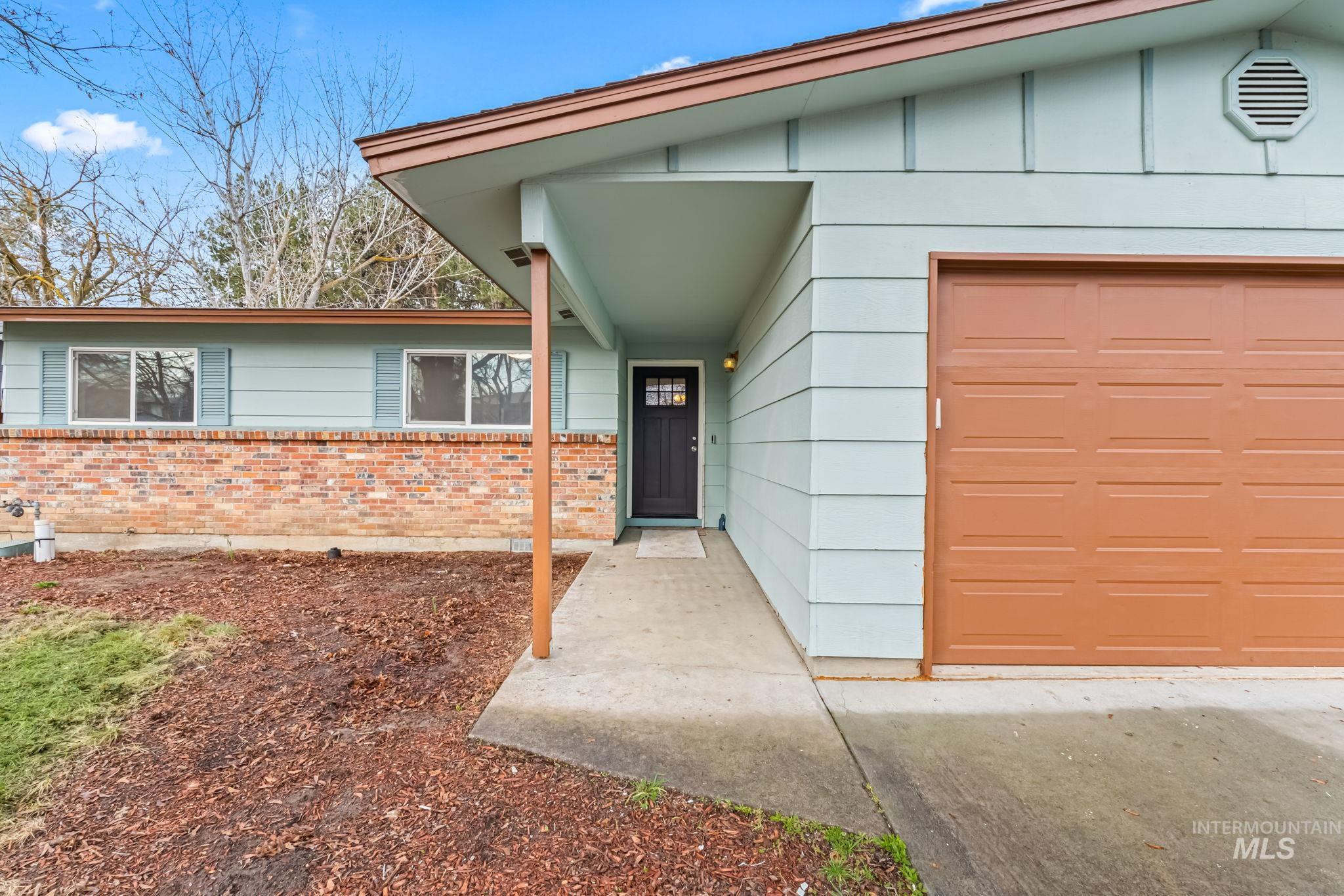 View of exterior entry with brick siding and an attached garage