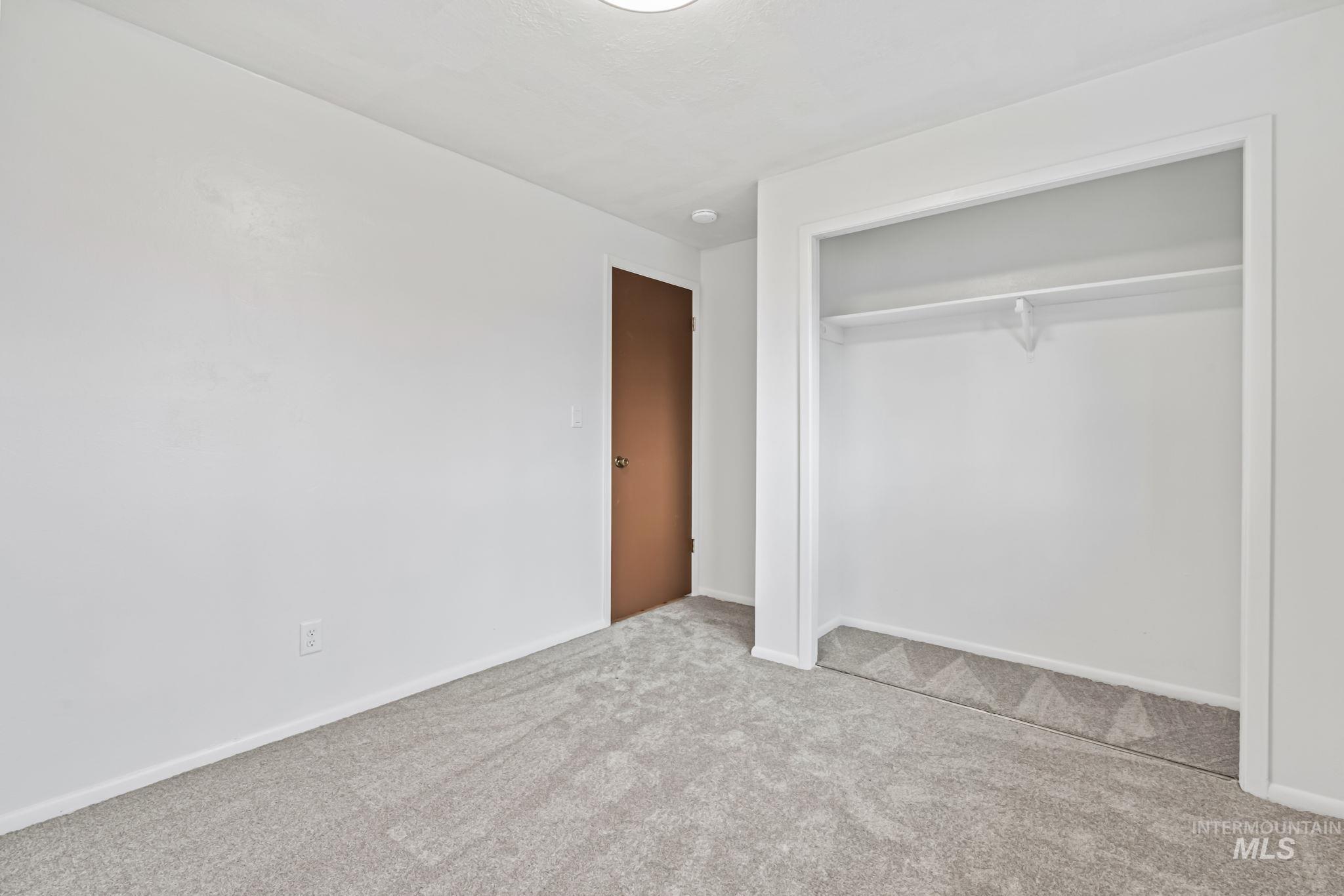 Unfurnished bedroom with light colored carpet and a closet