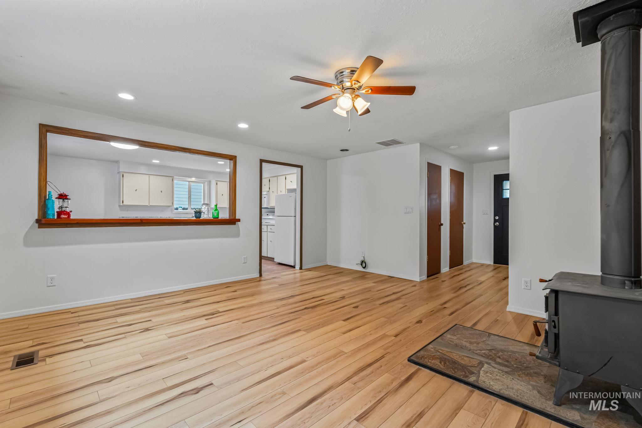 Unfurnished living room with a wood stove, a ceiling fan, recessed lighting, and light wood finished floors