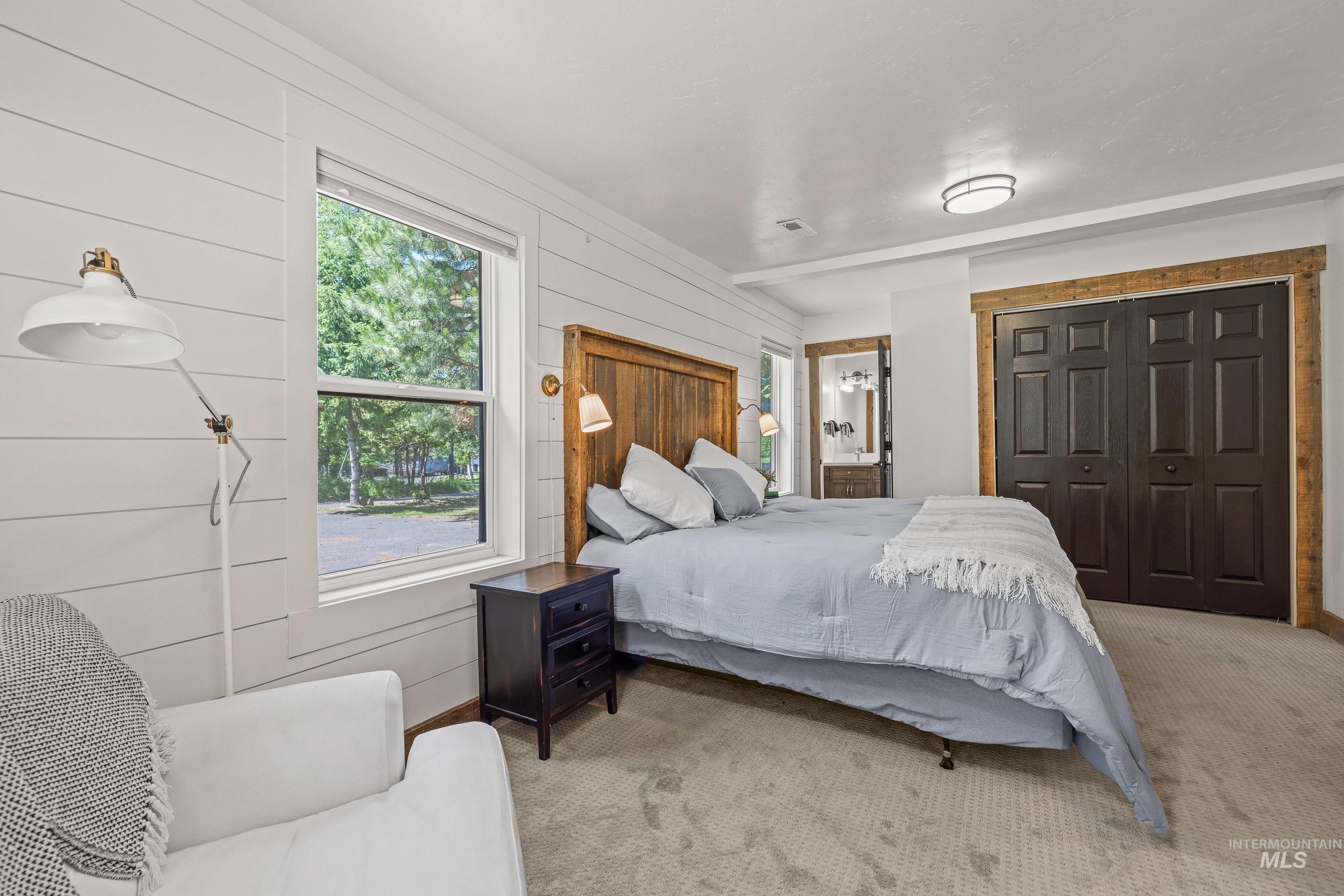 Carpeted bedroom featuring wooden walls