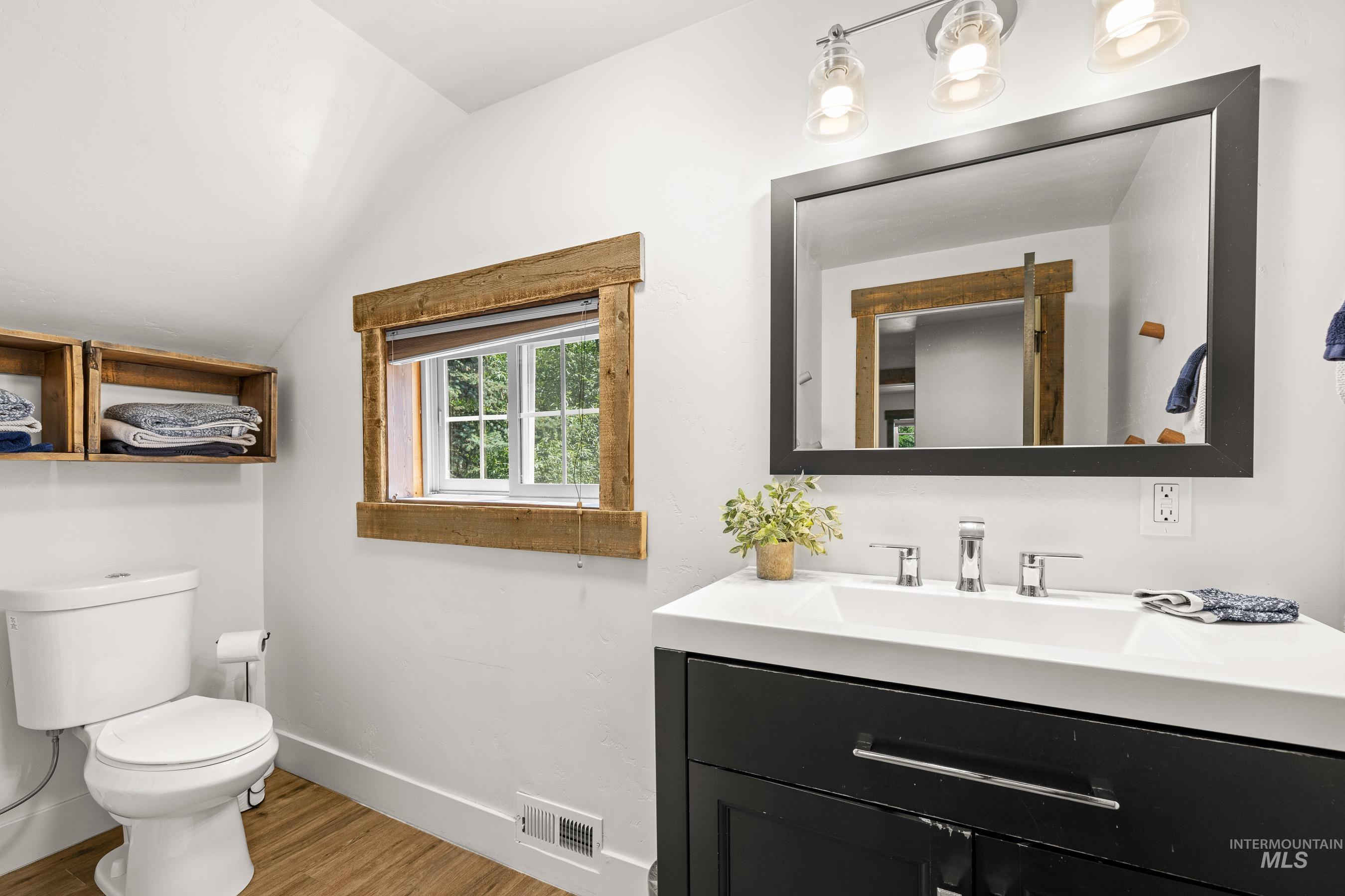 Bathroom with vanity, vaulted ceiling, and wood finished floors