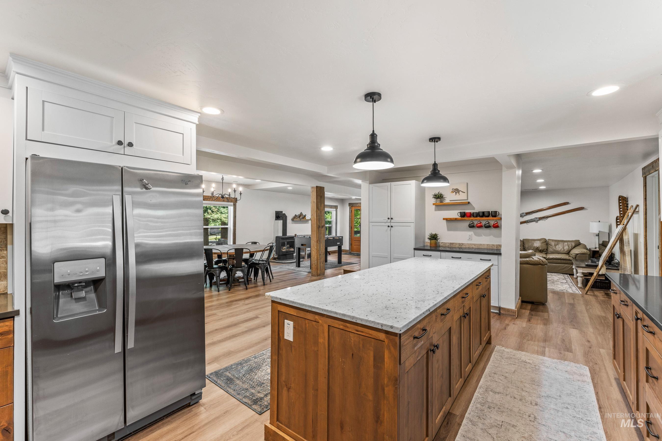 Kitchen with stainless steel fridge with ice dispenser, light wood-style floors, light stone countertops, white cabinetry, and recessed lighting