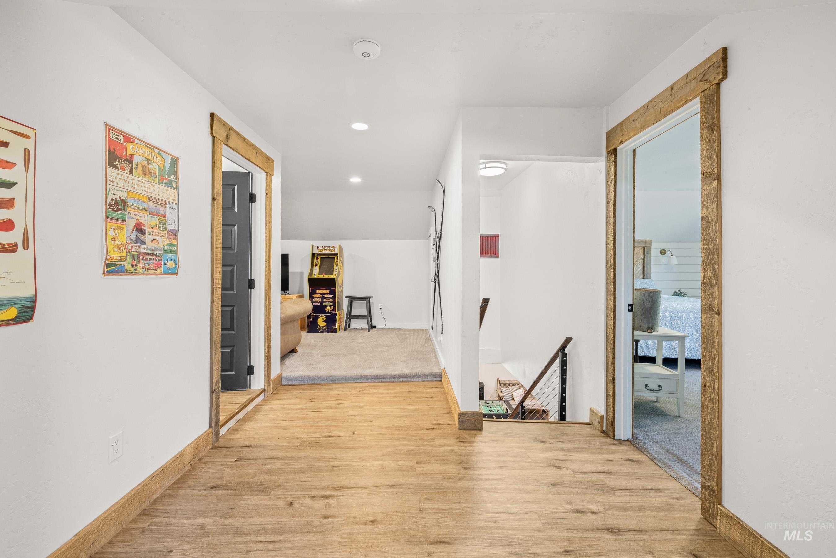 Hallway with an upstairs landing, light wood-style floors, and recessed lighting