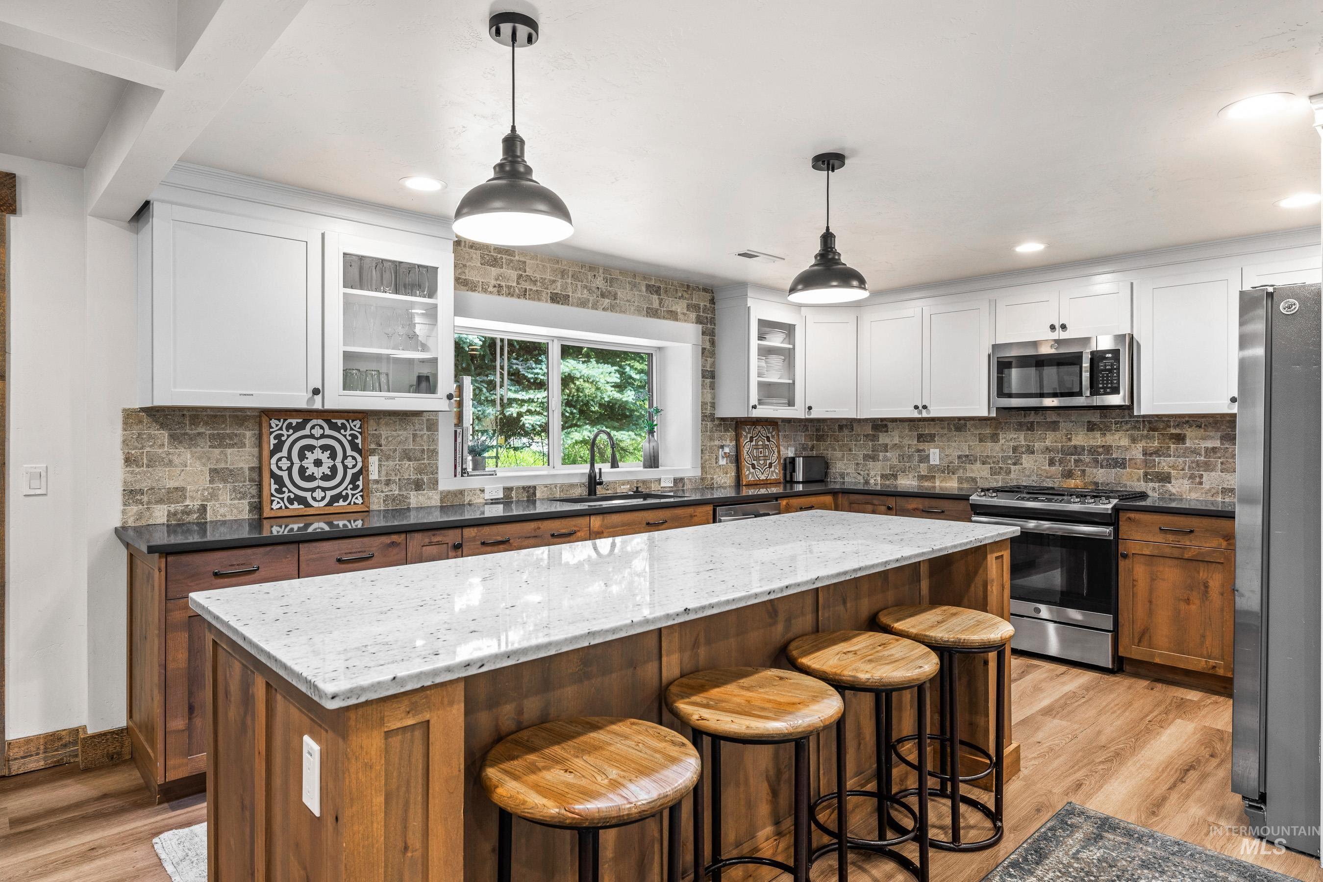 Kitchen featuring appliances with stainless steel finishes, light wood-style floors, a center island, decorative backsplash, and recessed lighting