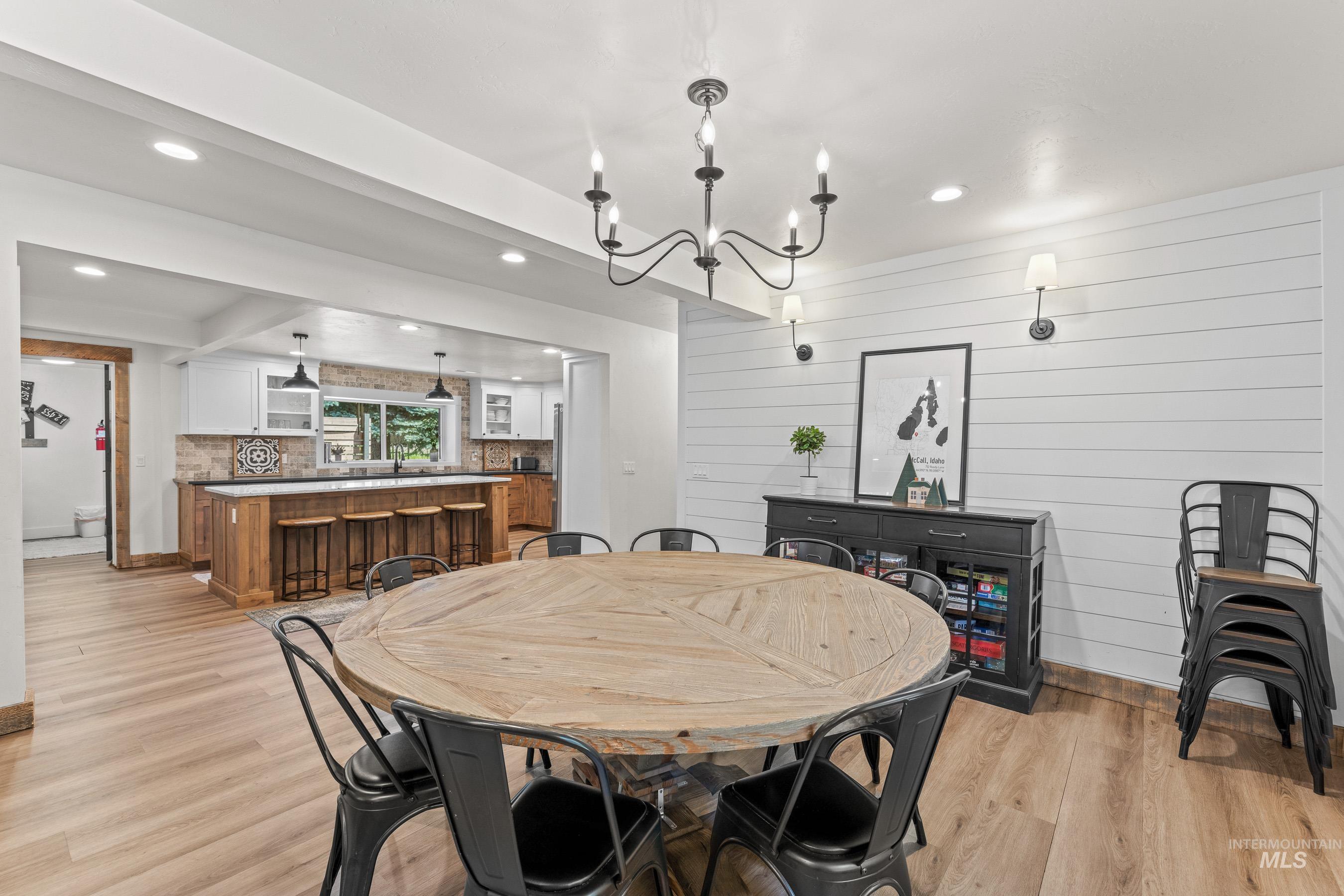 Dining room with light wood finished floors, a chandelier, recessed lighting, and wood walls