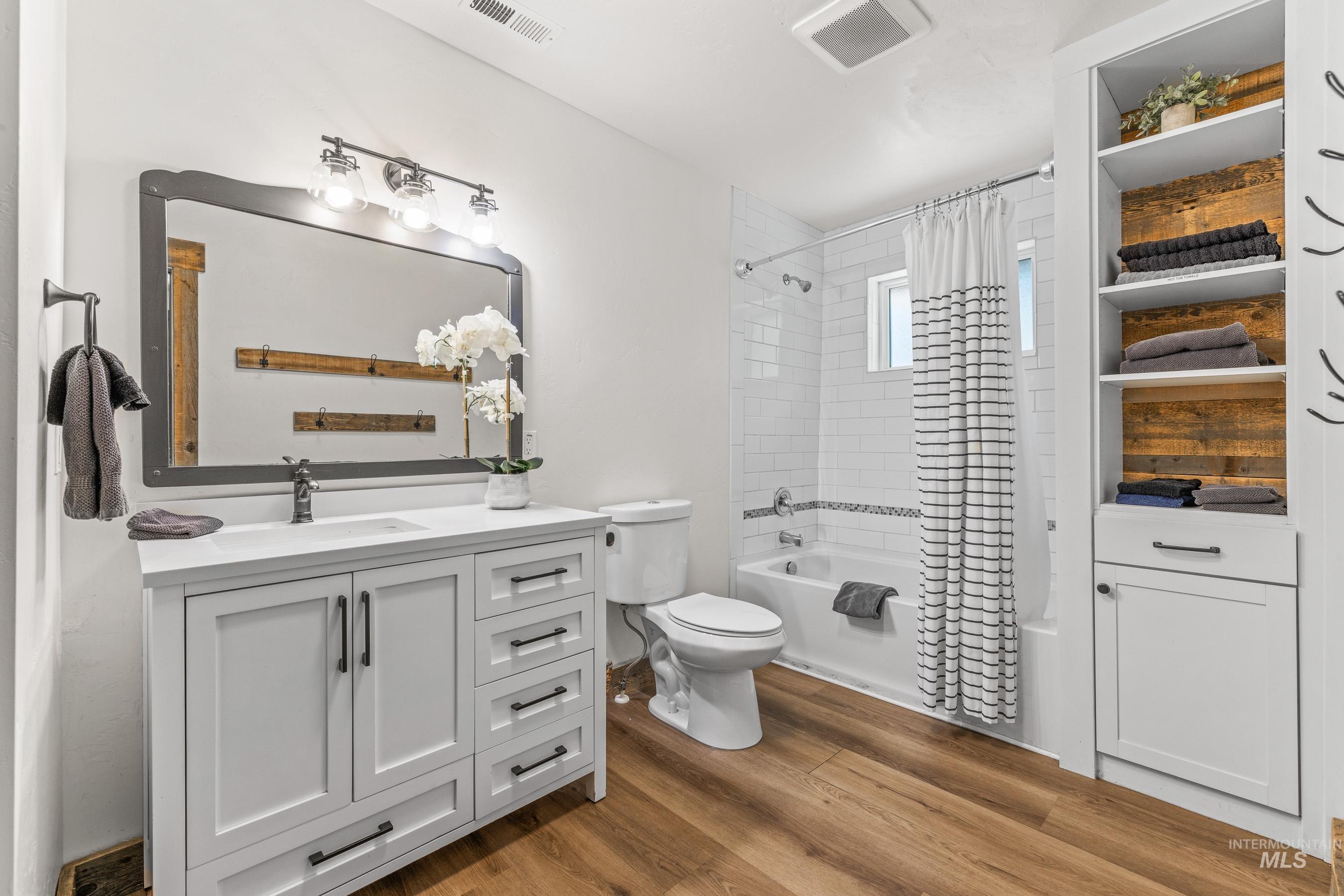 Full bath featuring wood finished floors, shower / tub combo, and vanity