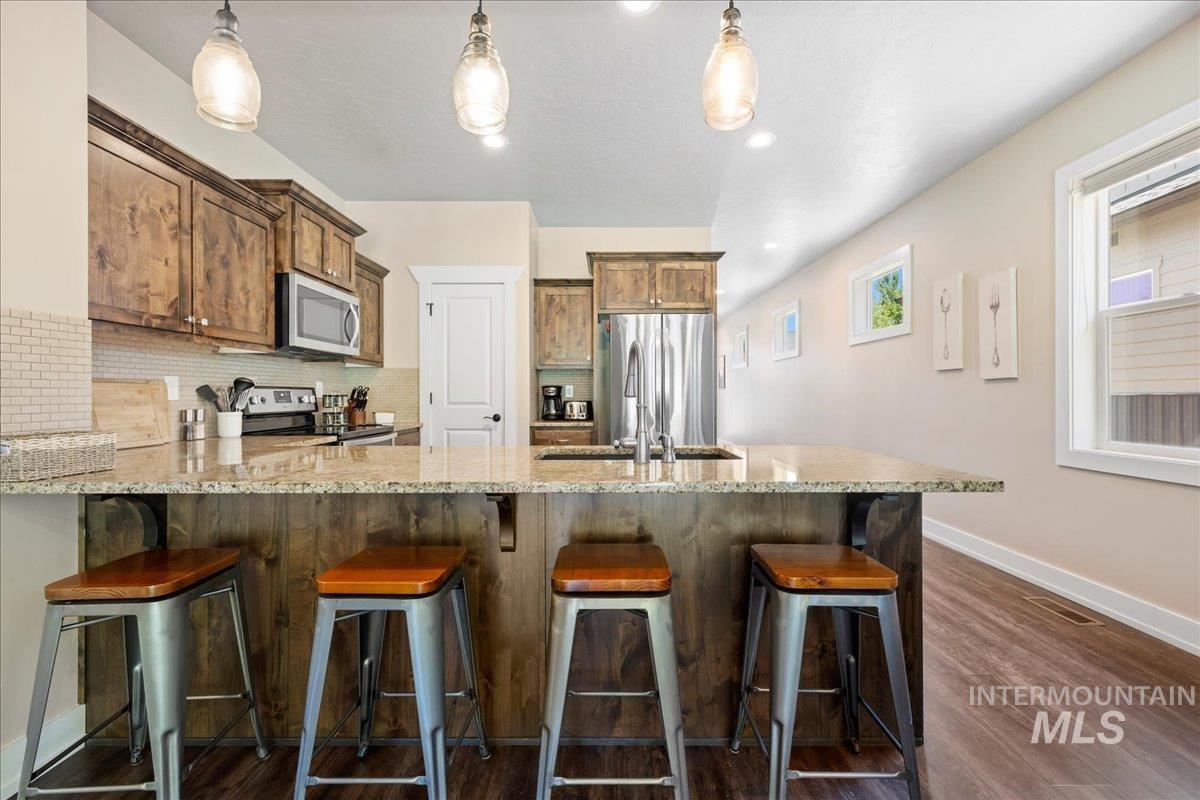 Kitchen featuring appliances with stainless steel finishes, tasteful backsplash, and light stone countertops