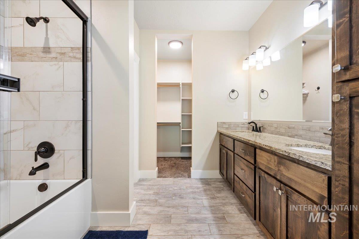 Full bath with tub / shower combination, double vanity, wood finished floors, and a spacious closet