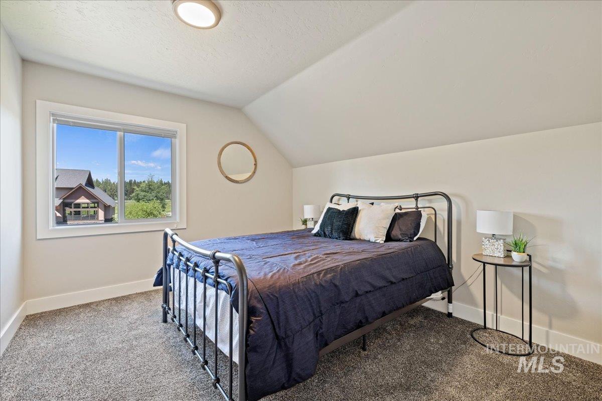 Bedroom featuring carpet, lofted ceiling, and a textured ceiling