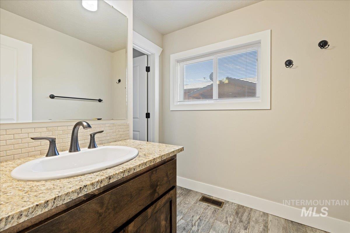 Bathroom with tasteful backsplash, vanity, and wood finished floors