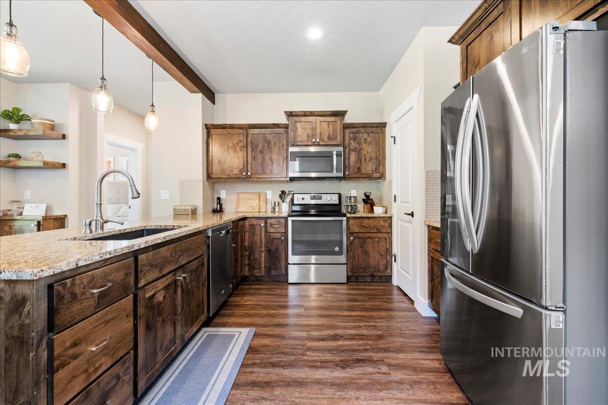 Kitchen with stainless steel appliances, a peninsula, open shelves, dark wood-style flooring, and backsplash