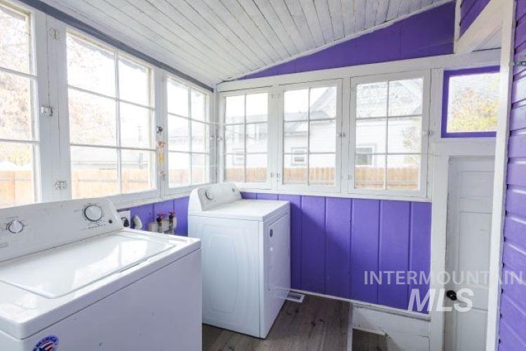 Laundry room with dark wood finished floors, lofted ceiling, independent washer and dryer, wooden ceiling, and a sunroom