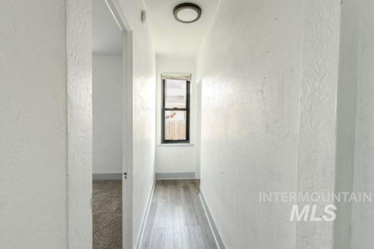 Hallway featuring a textured wall and light wood-style floors
