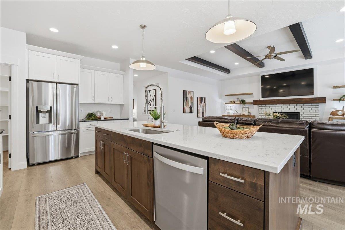 Kitchen featuring appliances with stainless steel finishes, dark brown cabinetry, open floor plan, white cabinets, and a fireplace