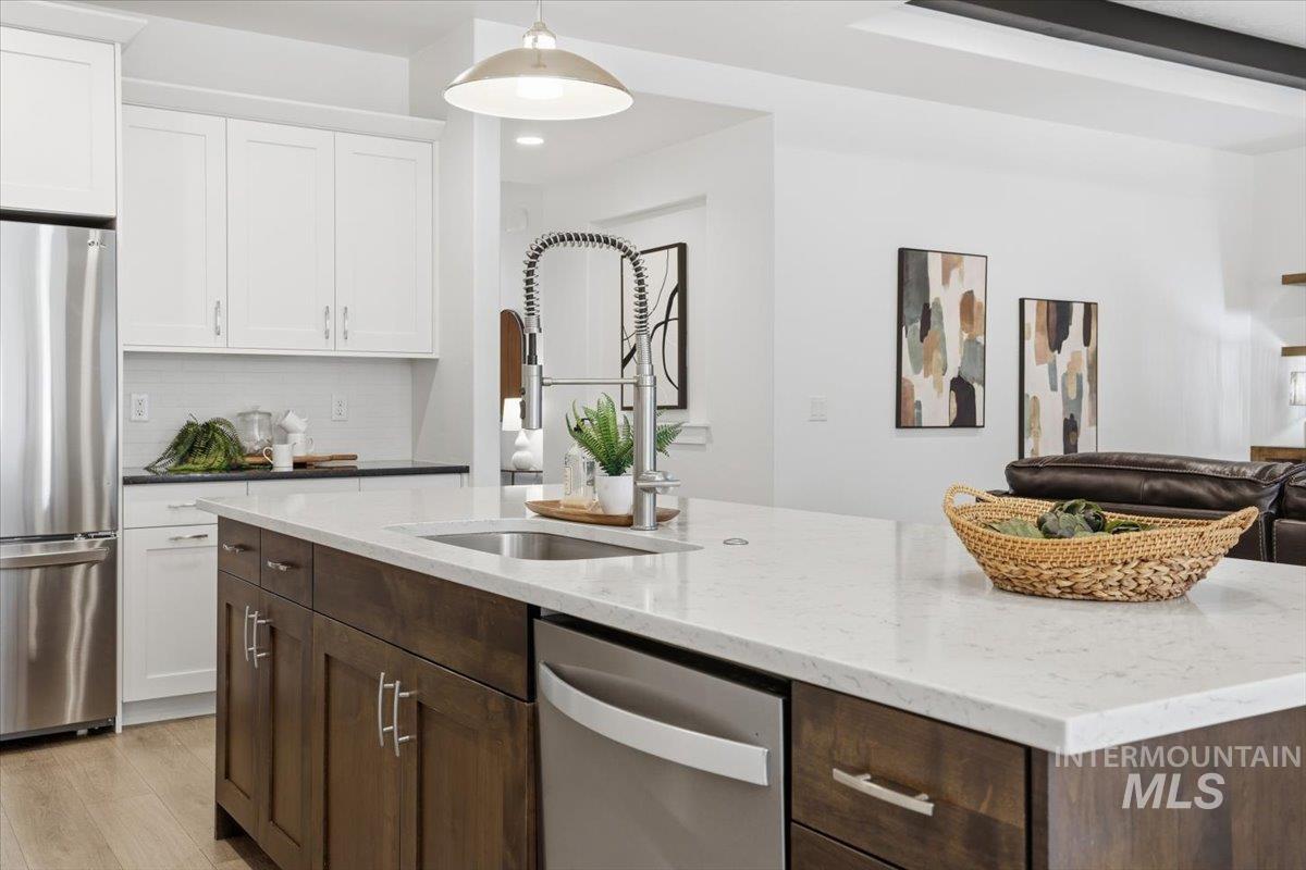 Kitchen featuring dark brown cabinets, stainless steel appliances, dark stone countertops, white cabinetry, and tasteful backsplash