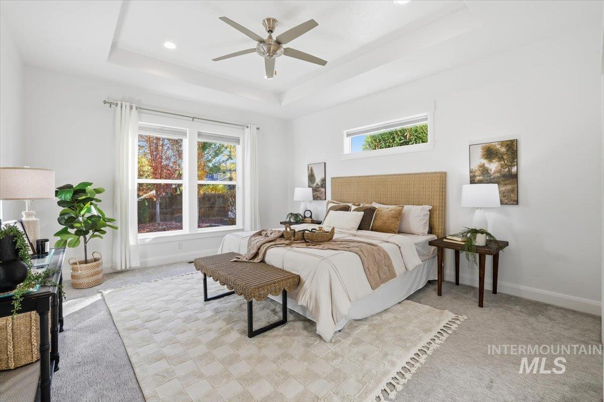 Carpeted bedroom with a tray ceiling, a ceiling fan, and recessed lighting