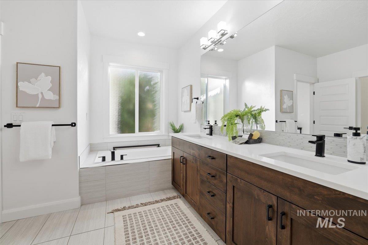 Bathroom with double vanity, a garden tub, and light tile patterned floors