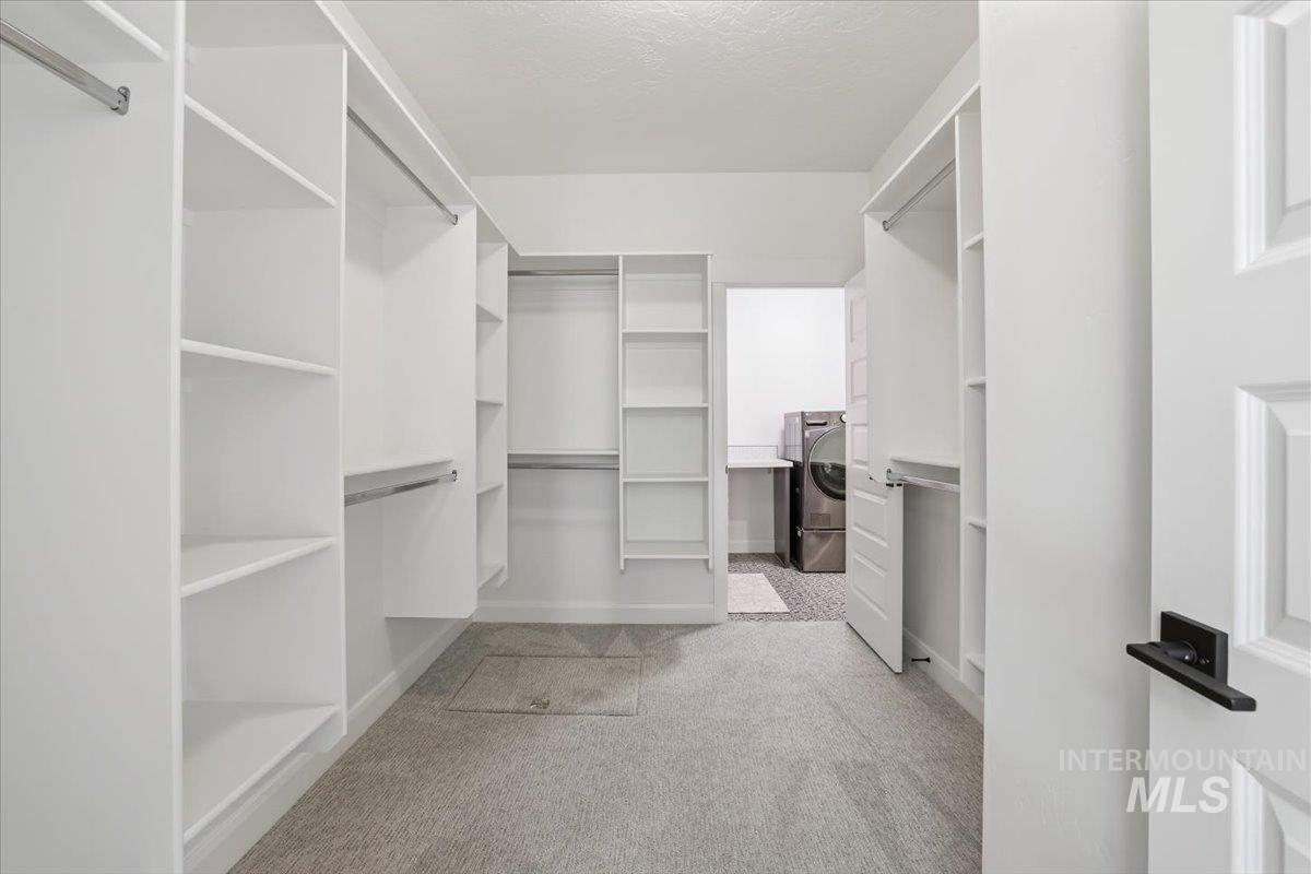 Walk in closet featuring light carpet and washer / dryer